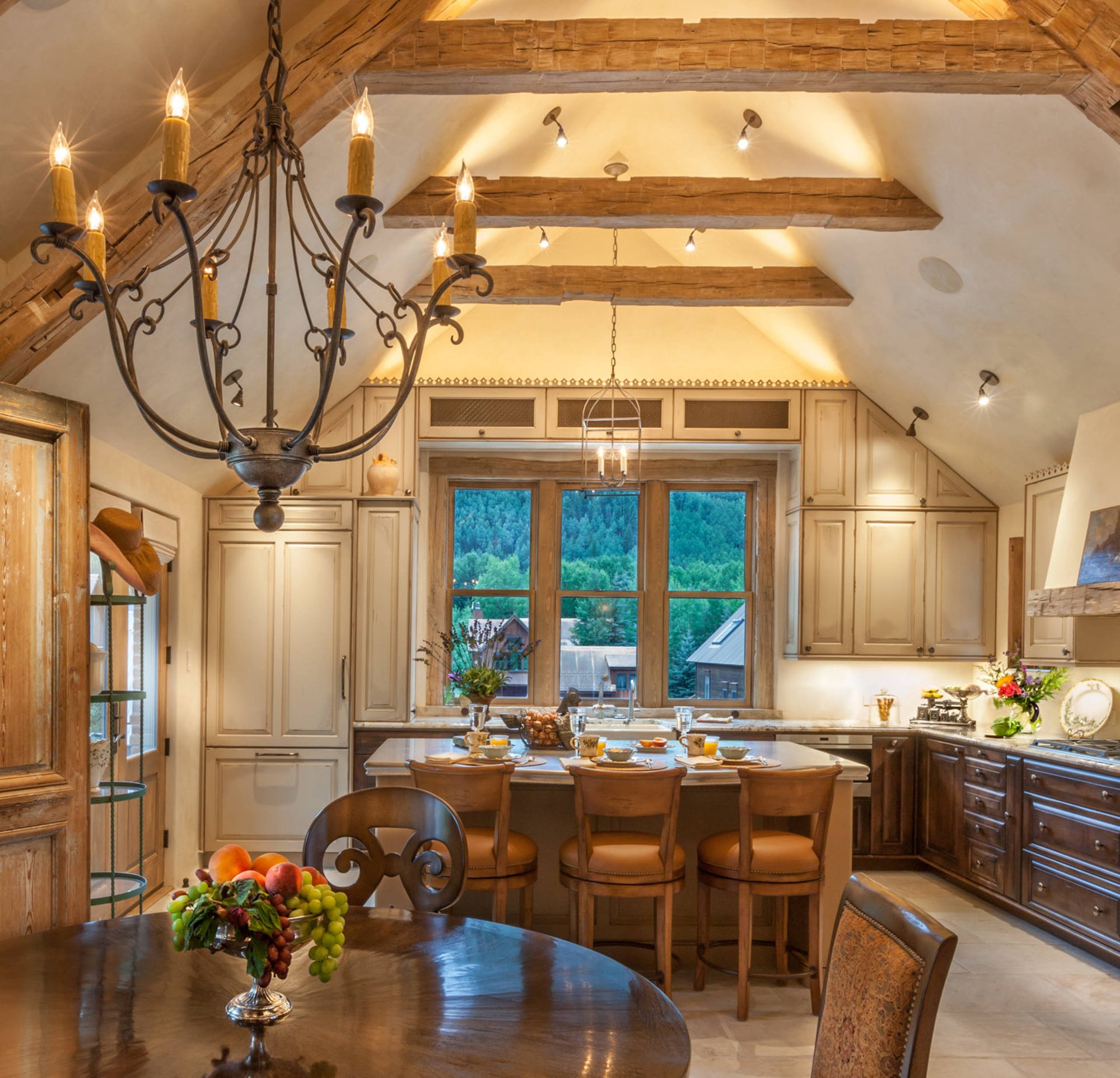 Elegant l-shaped ceramic tile open concept kitchen with a farmhouse sink, raised-panel cabinets, paneled appliances, an island, dark wood cabinets and granite countertops, by Jensen Design in Telluride, CO