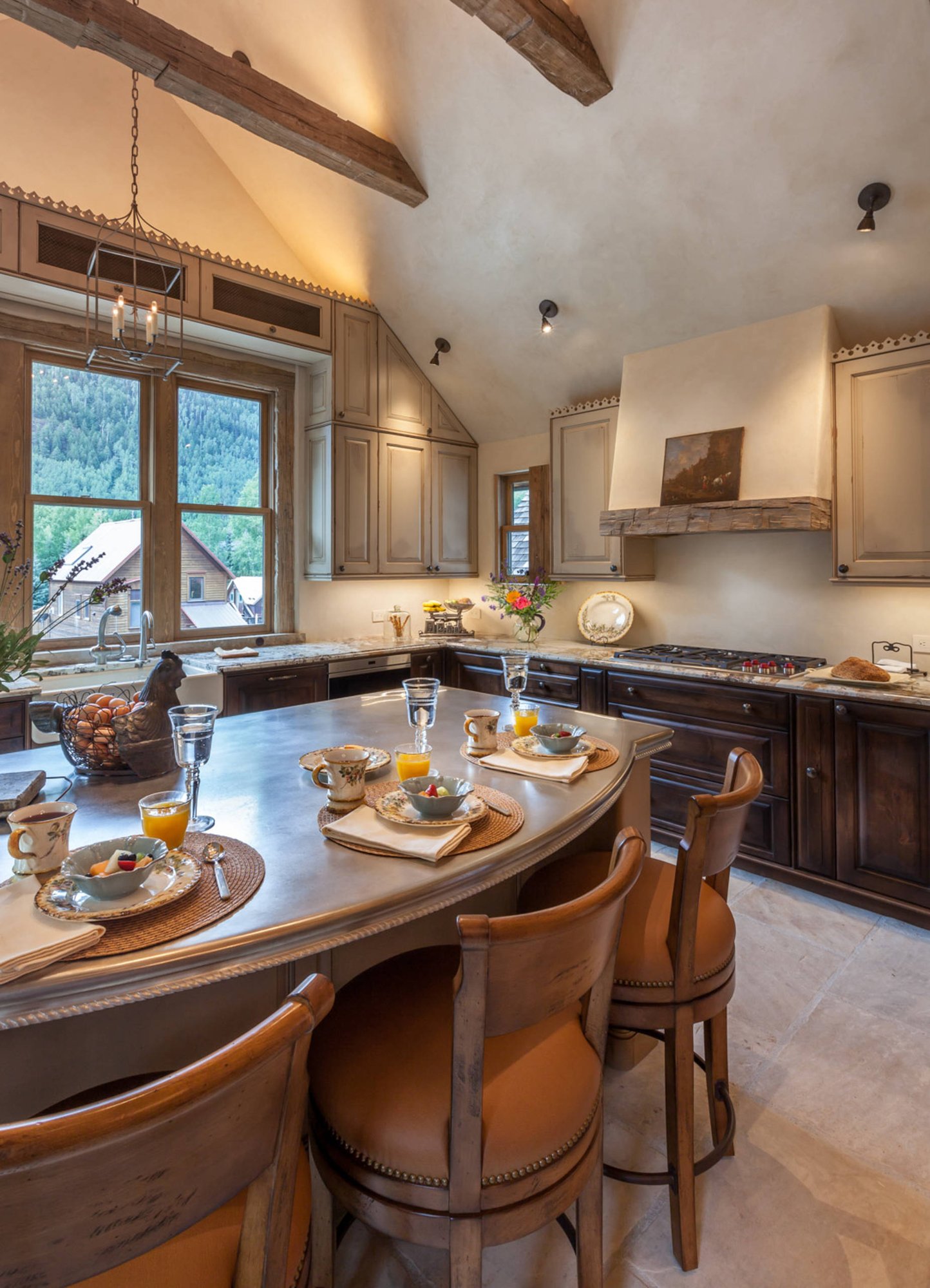 Mid-sized classic l-shaped ceramic tile open concept kitchen with a farmhouse sink, raised-panel cabinets, paneled appliances, an island, dark wood cabinets and granite countertops, by Jensen Design in Telluride, CO