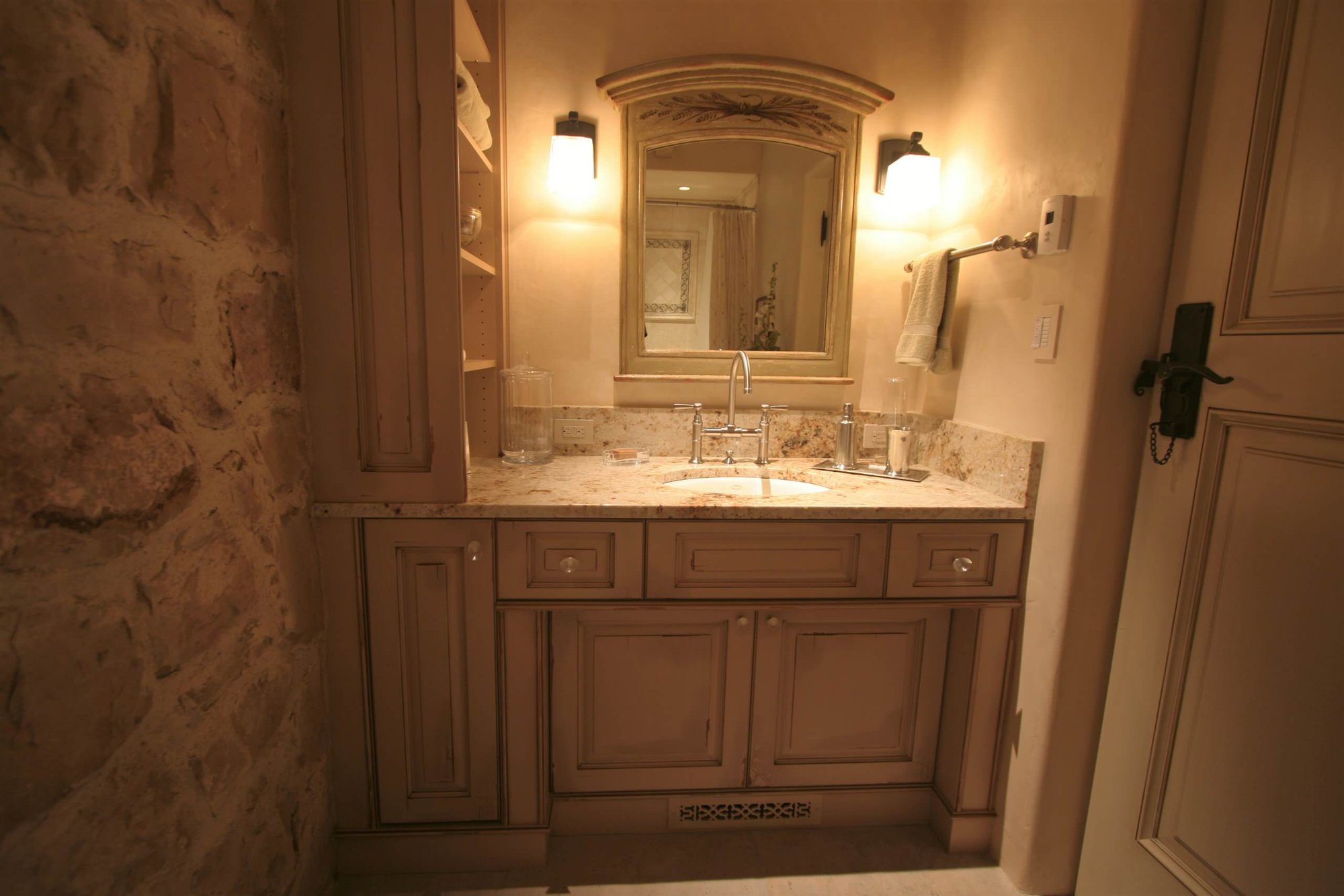 Mid-sized traditional 3/4 beige tile porcelain tile bathroom with raised-panel cabinets, beige walls, an undermount sink, granite countertops and distressed cabinets, by Jensen Design in Telluride, CO