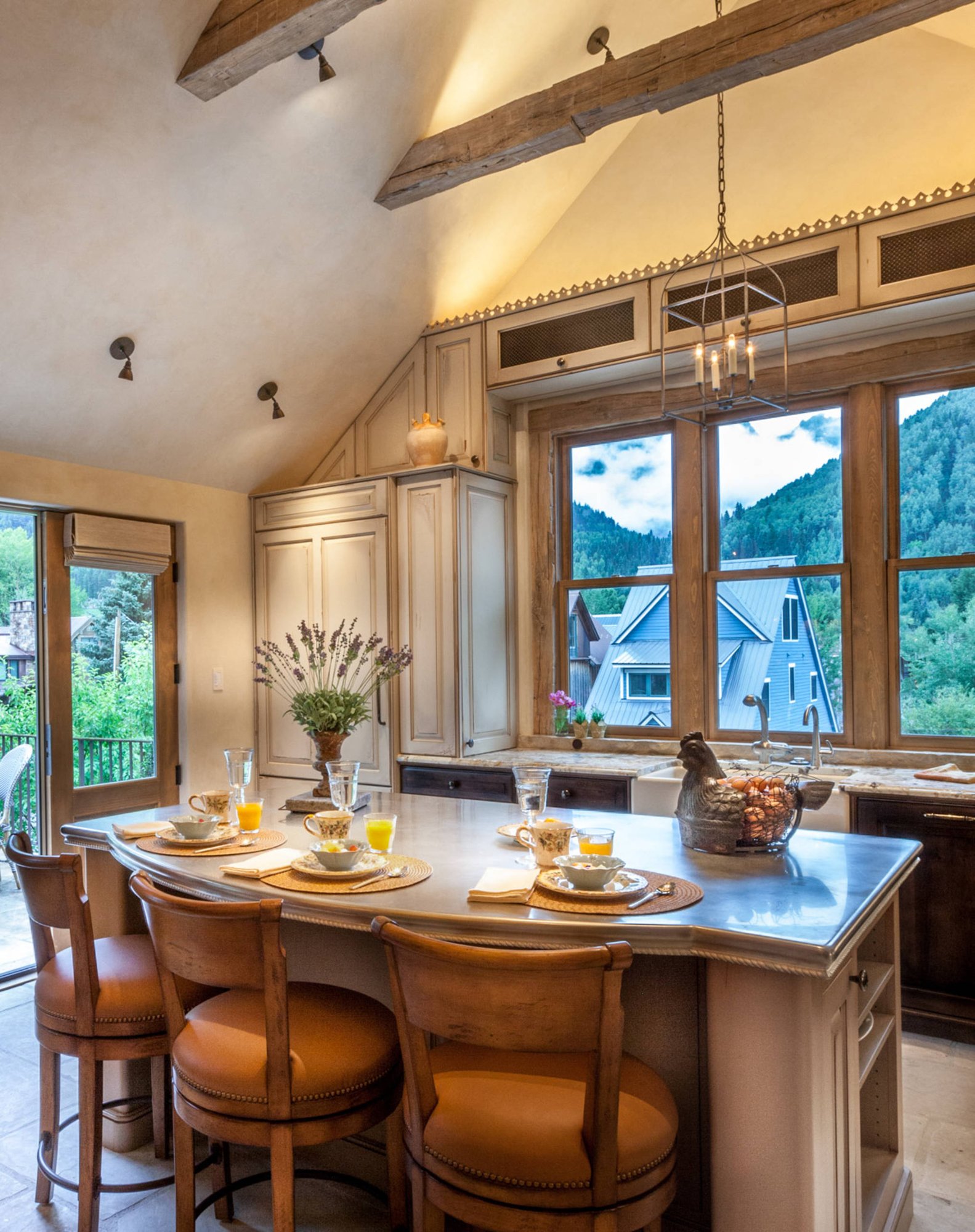 Mid-sized classic l-shaped ceramic tile open concept kitchen with raised-panel cabinets, paneled appliances, an island, a farmhouse sink, dark wood cabinets and granite countertops, by Jensen Design in Telluride, CO