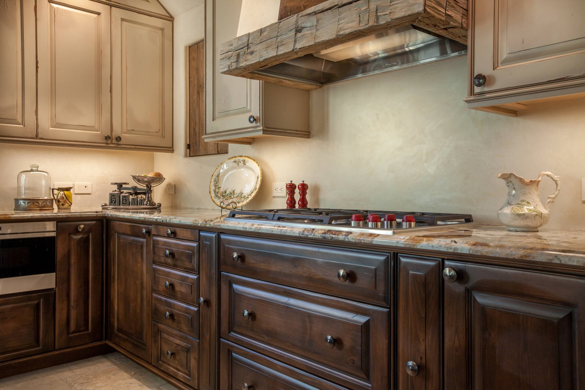 Mid-sized elegant l-shaped ceramic tile open concept kitchen with raised-panel cabinets, paneled appliances, an island, a farmhouse sink, dark wood cabinets and granite countertops, by Jensen Design in Telluride, CO