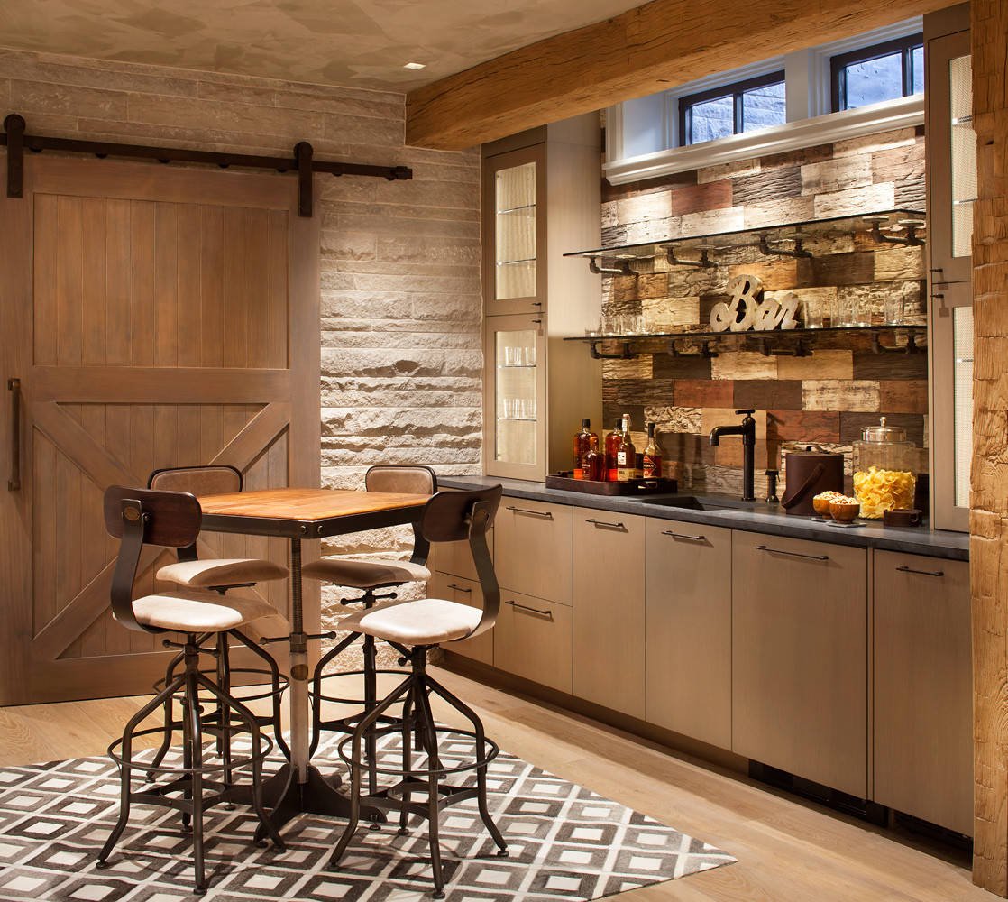 Mountain style light wood floor home bar with an undermount sink, flat-panel cabinets, medium tone wood cabinets and wood backsplash, by Jensen Design in Telluride, CO
