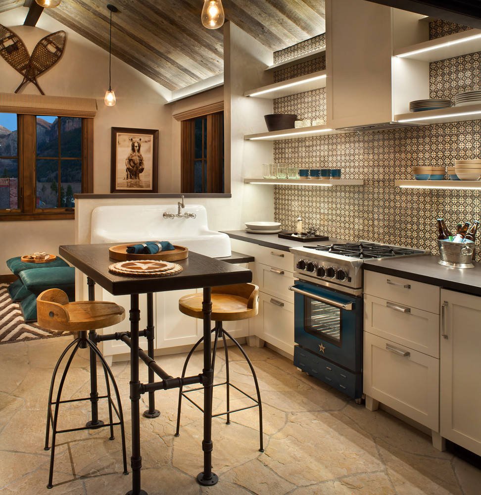 Rustic l-shaped kitchen with a farmhouse sink, shaker cabinets, white cabinets, multicolored backsplash, colored appliances and an island, by Jensen Design in Telluride, CO