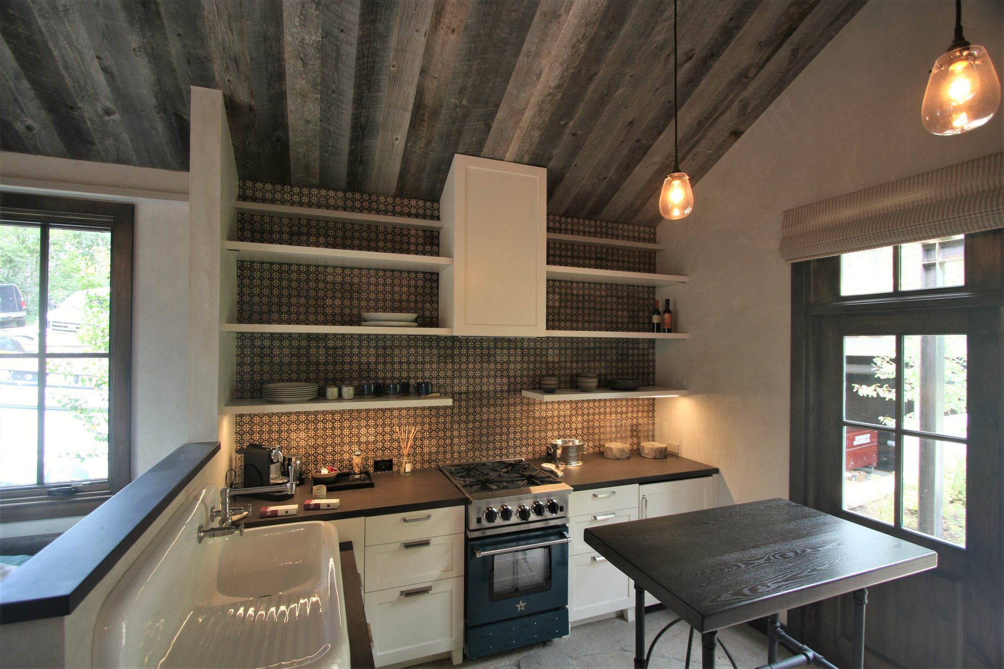 Small craftsman l-shaped concrete floor open concept kitchen with an integrated sink, shaker cabinets, white cabinets, black appliances, an island, concrete countertops, multicolored backsplash and mosaic tile backsplash, by Jensen Design in Telluride, CO