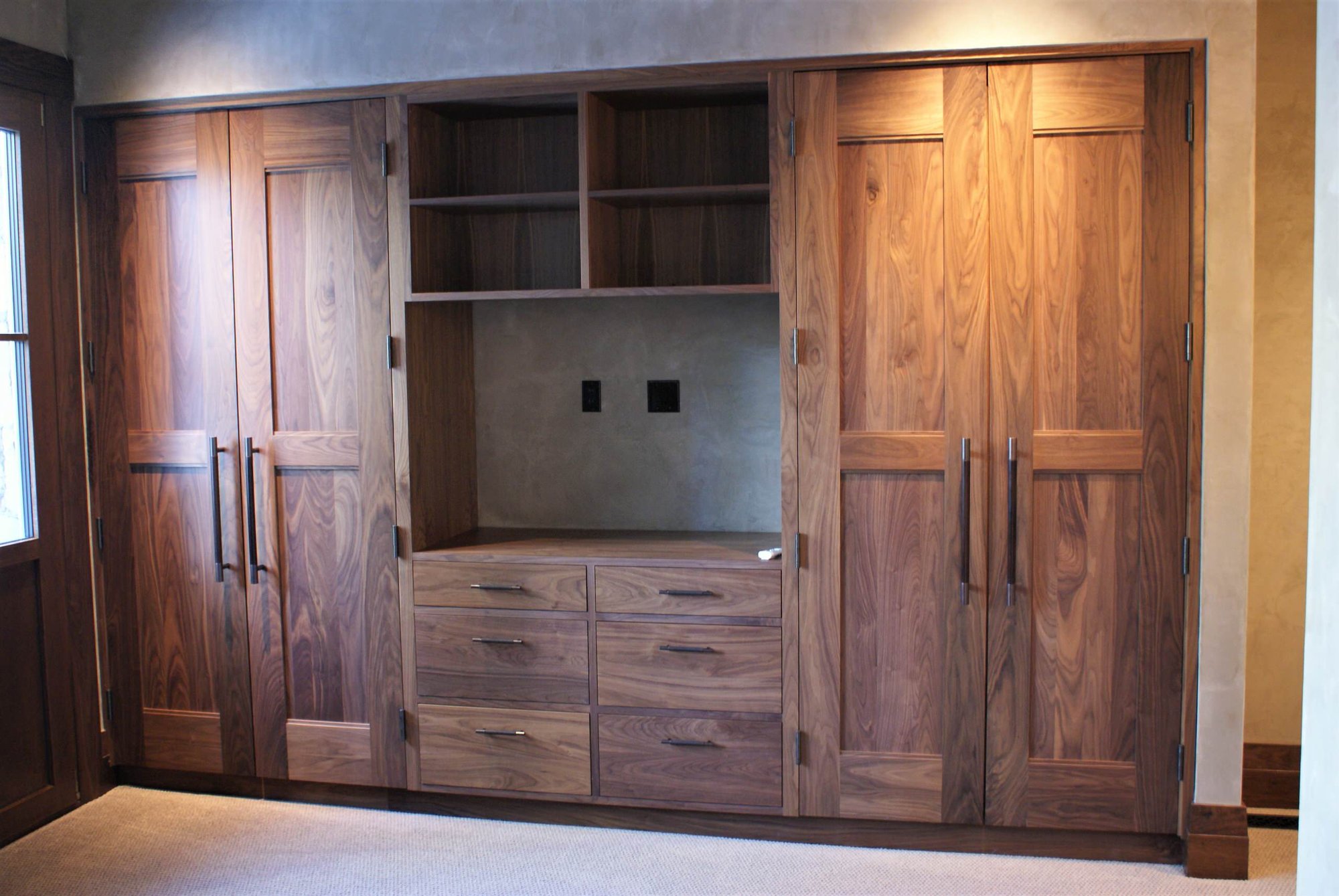 Large elegant gender-neutral carpeted dressing room with recessed-panel cabinets and medium tone wood cabinets, by Jensen Design in Telluride, CO