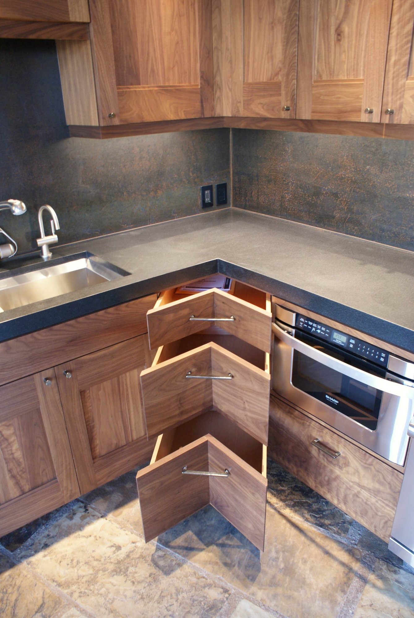 Mid-sized craftsman l-shaped slate floor open concept kitchen with black backsplash, a double-bowl sink, shaker cabinets, dark wood cabinets, concrete countertops, stone slab backsplash, stainless steel appliances and no island, by Jensen Design in Telluride, CO