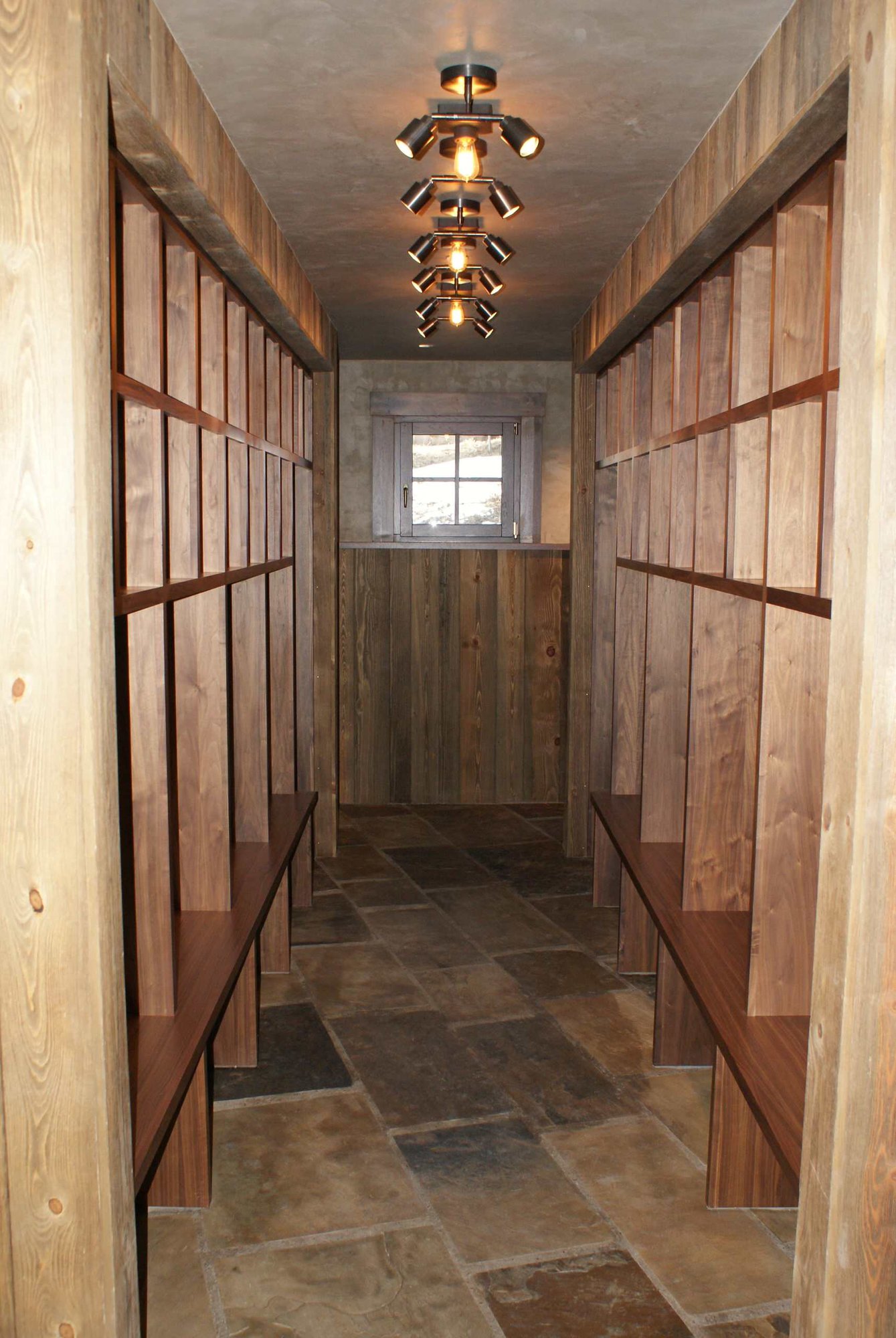 Large classic gender-neutral dressing room with open cabinets and medium tone wood cabinets, by Jensen Design in Telluride, CO