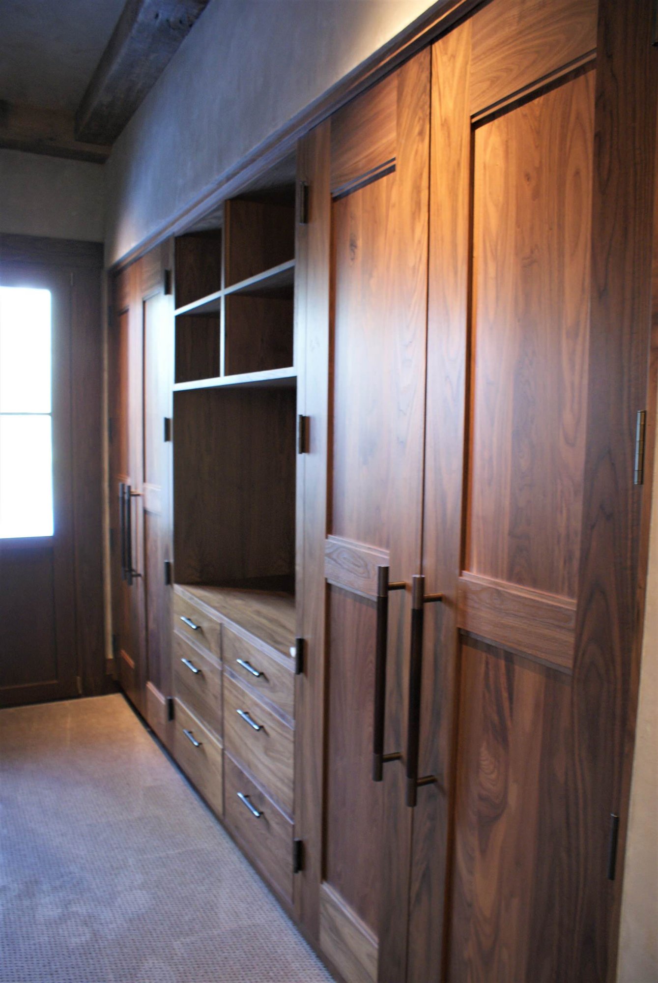 Large timeless gender-neutral carpeted dressing room with recessed-panel cabinets and medium tone wood cabinets, by Jensen Design in Telluride, CO