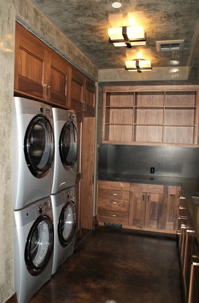 Large arts and crafts u-shaped concrete floor utility room with an undermount sink, flat-panel cabinets, dark wood cabinets, gray walls and a side-by-side washer/dryer, by Jensen Design in Telluride, CO