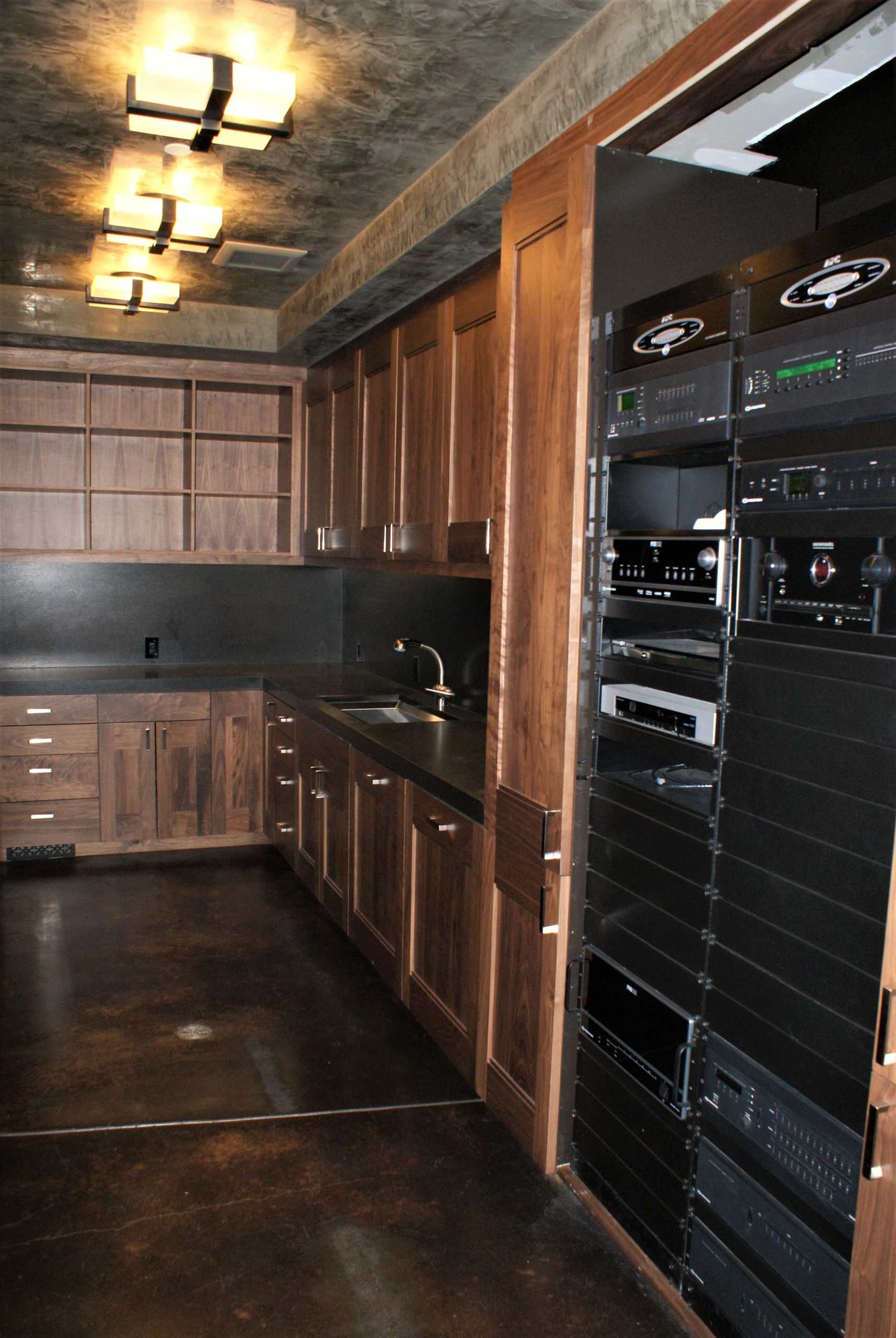 Large arts and crafts u-shaped concrete floor utility room with an undermount sink, flat-panel cabinets, dark wood cabinets, gray walls and a side-by-side washer/dryer, by Jensen Design in Telluride, CO