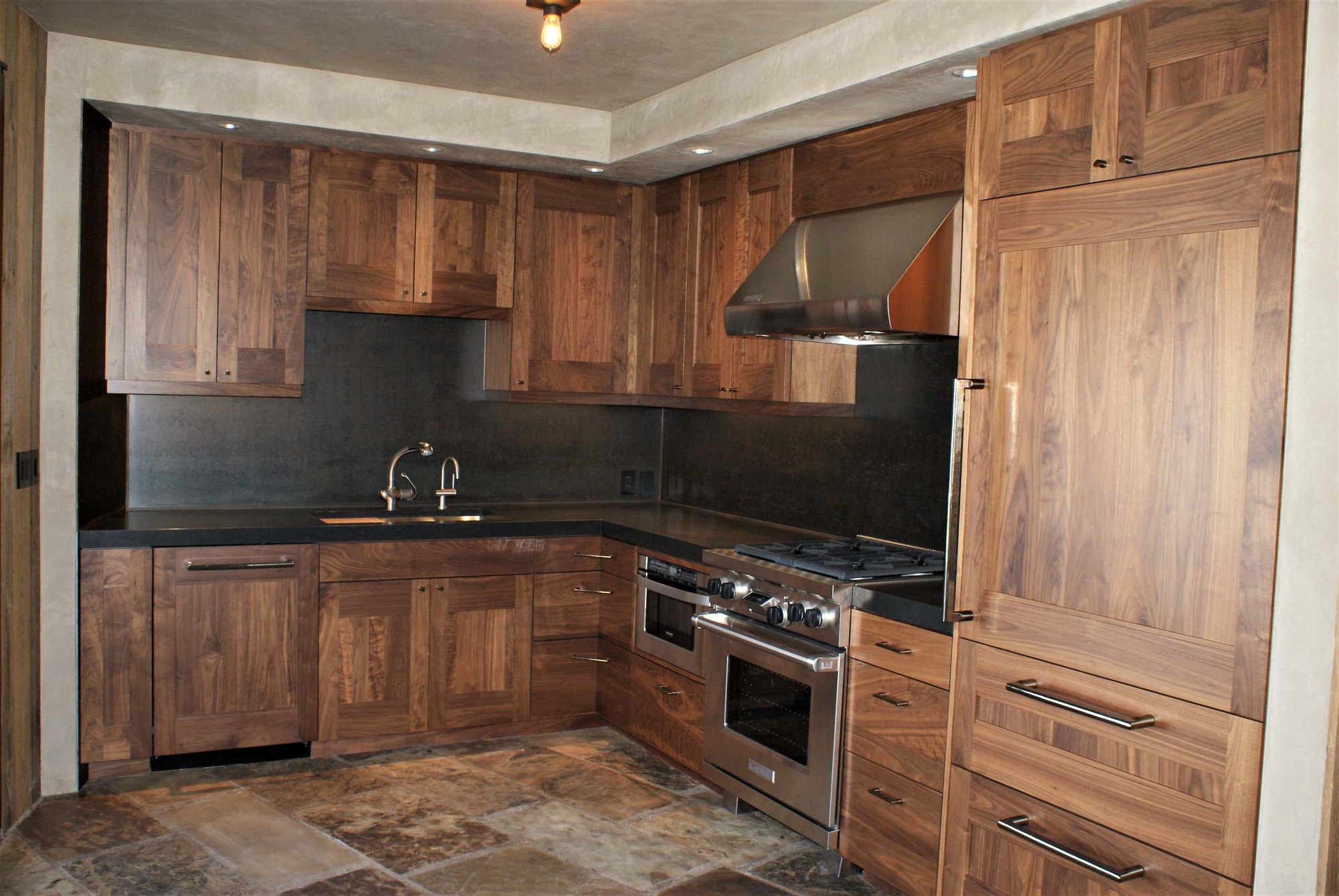 Mid-sized arts and crafts l-shaped slate floor open concept kitchen with black backsplash, a double-bowl sink, shaker cabinets, dark wood cabinets, concrete countertops, stone slab backsplash, stainless steel appliances and no island, by Jensen Design in Telluride, CO