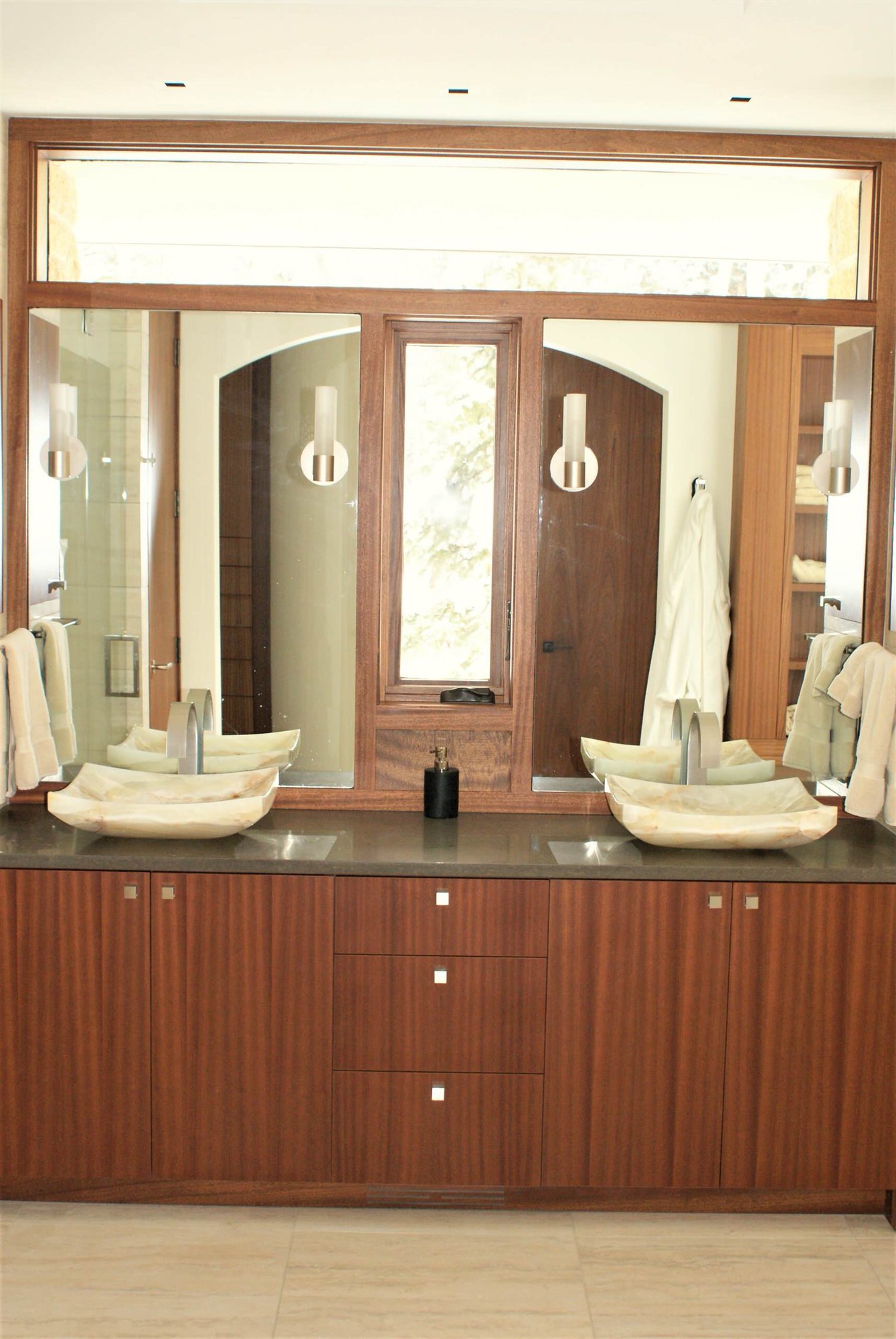 Mid-sized trendy master porcelain tile bathroom with flat-panel cabinets, medium tone wood cabinets, a vessel sink, beige walls, solid surface countertops and an undermount tub, by Jensen Design in Telluride, CO