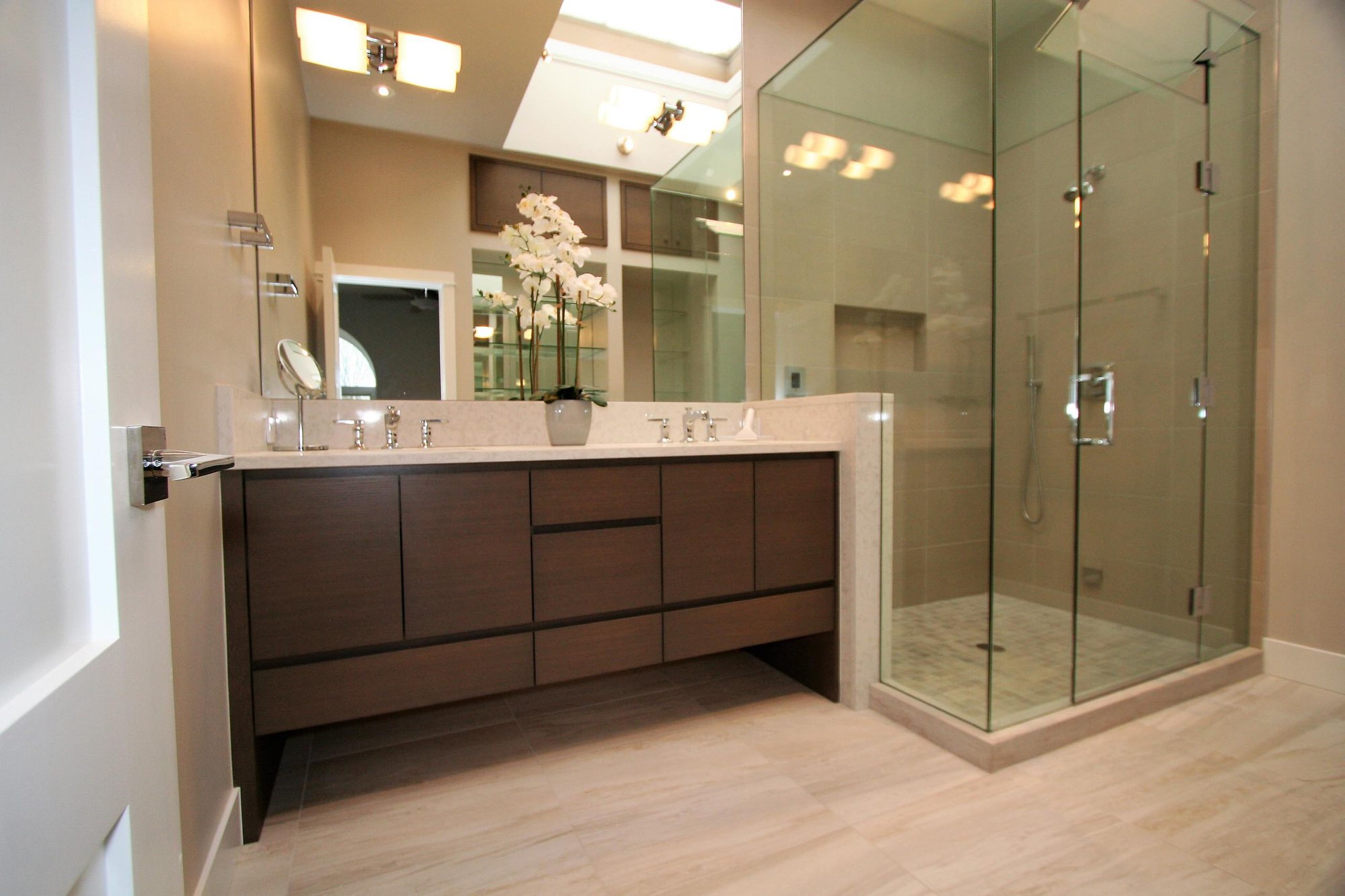 Mid-sized trendy master corner shower with flat-panel cabinets, medium tone wood cabinets, an undermount sink, marble countertops and a hinged shower door, by Jensen Design in Telluride, CO