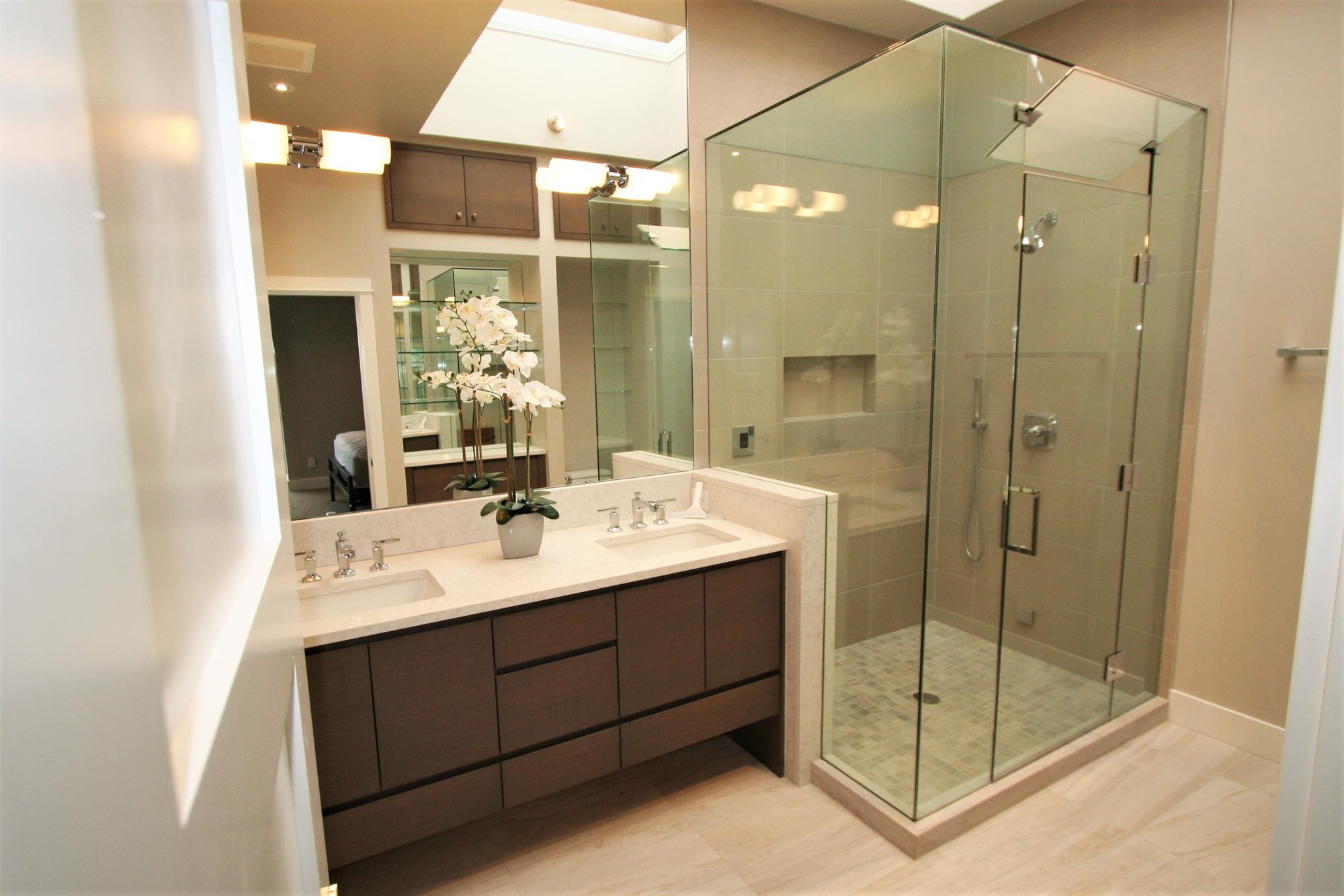 Mid-sized trendy master corner shower with flat-panel cabinets, medium tone wood cabinets, an undermount sink, marble countertops and a hinged shower door, by Jensen Design in Telluride, CO