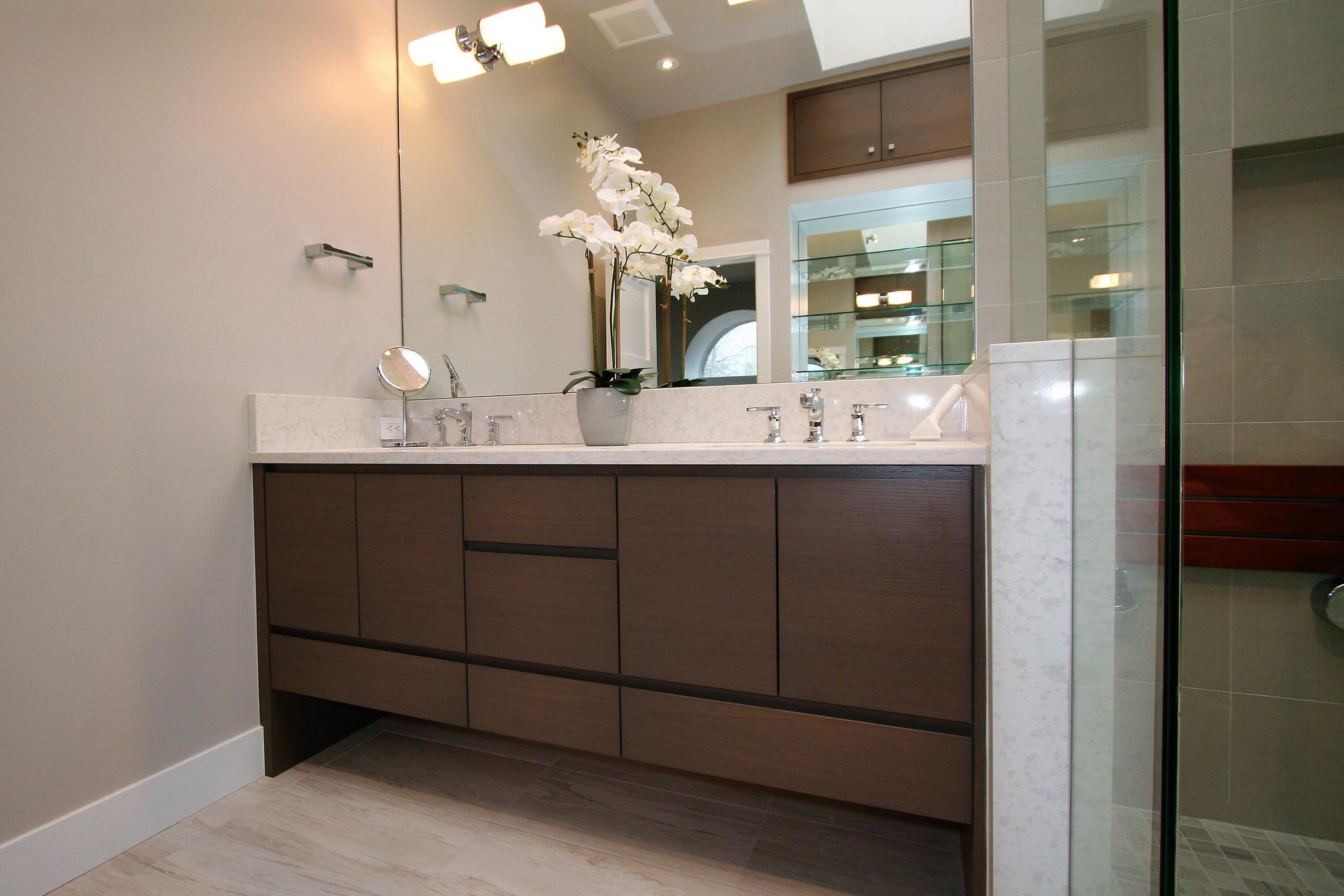Mid-sized trendy master corner shower with flat-panel cabinets, medium tone wood cabinets, an undermount sink, marble countertops and a hinged shower door, by Jensen Design in Telluride, CO