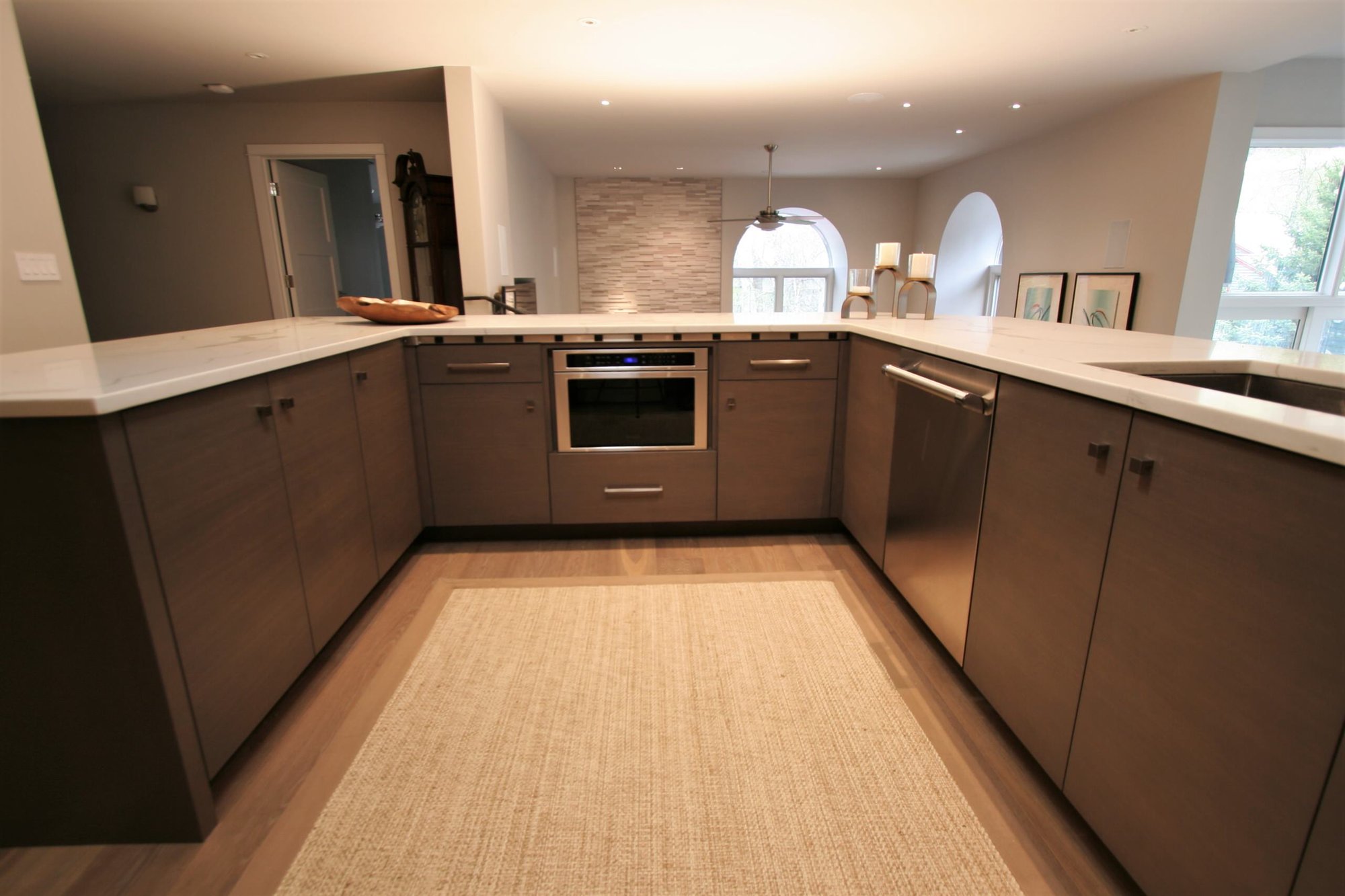 Mid-sized contemporary u-shaped medium tone wood floor open concept kitchen with an undermount sink, flat-panel cabinets, medium tone wood cabinets, marble countertops, white backsplash, marble backsplash, stainless steel appliances and a peninsula, by Jensen Design in Telluride, CO