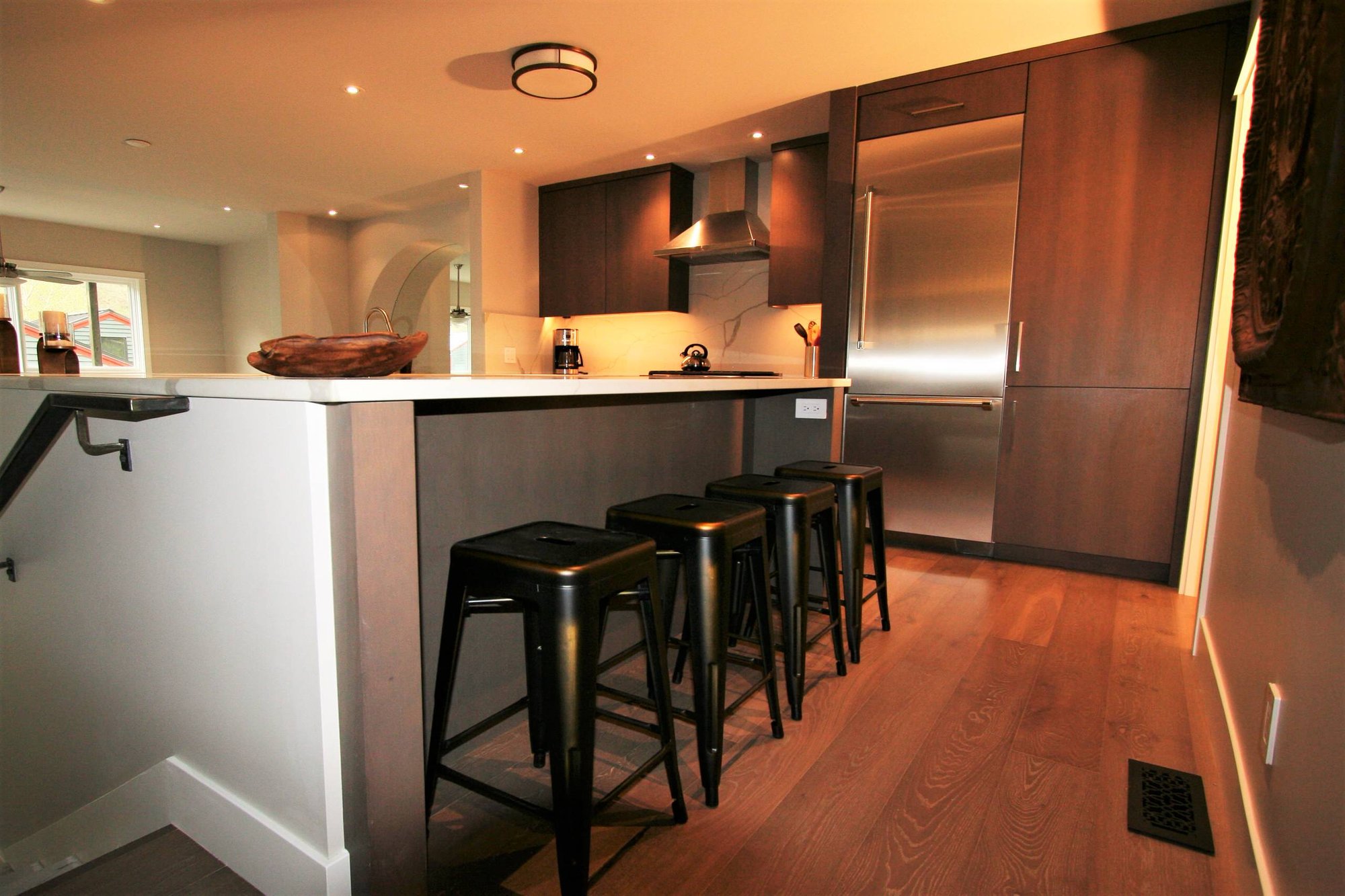 Mid-sized trendy u-shaped medium tone wood floor open concept kitchen with flat-panel cabinets, medium tone wood cabinets, marble countertops, white backsplash, marble backsplash, stainless steel appliances and a peninsula, by Jensen Design in Telluride, CO
