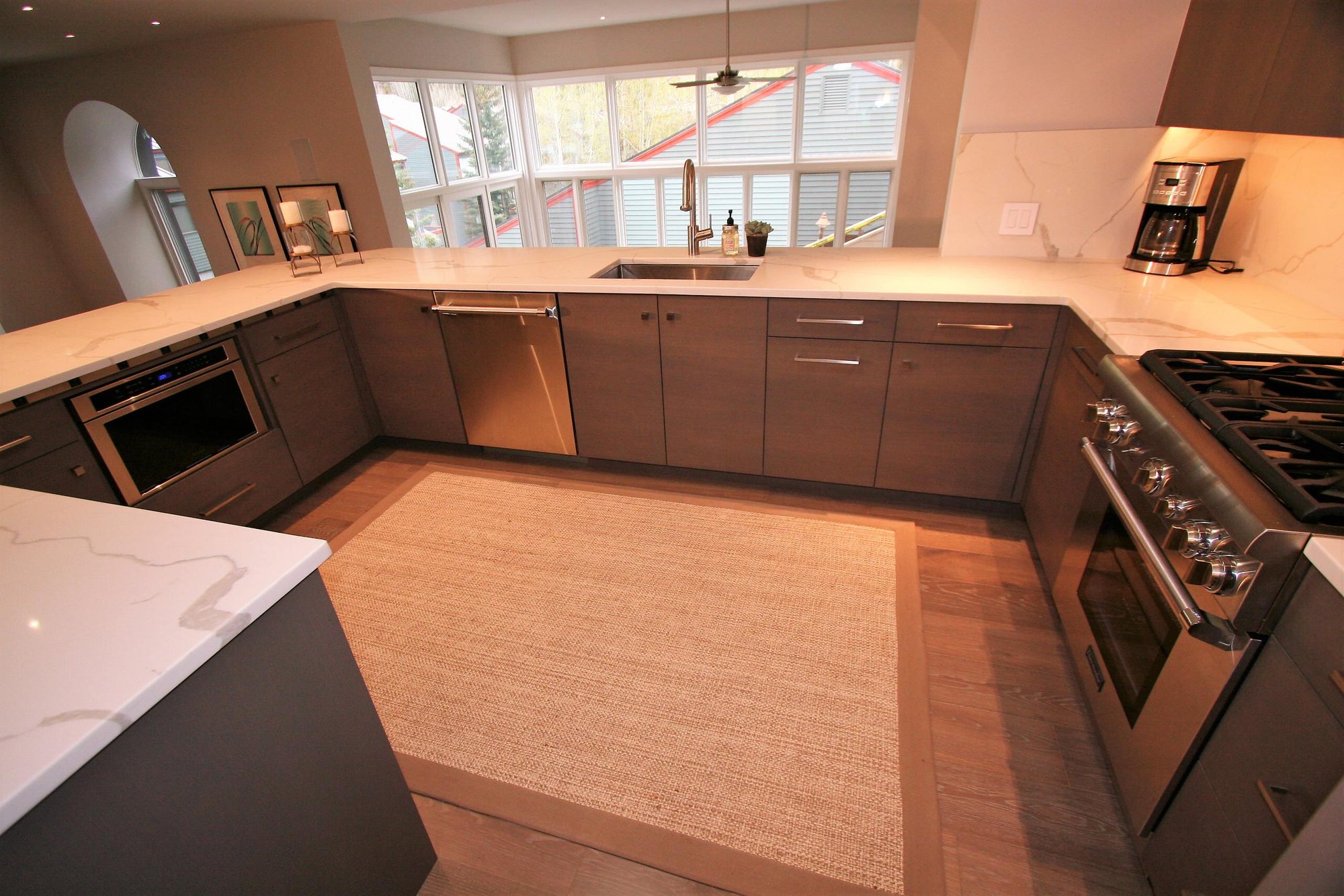 Mid-sized trendy u-shaped medium tone wood floor open concept kitchen with an undermount sink, flat-panel cabinets, medium tone wood cabinets, marble countertops, white backsplash, marble backsplash, stainless steel appliances and a peninsula, by Jensen Design in Telluride, CO