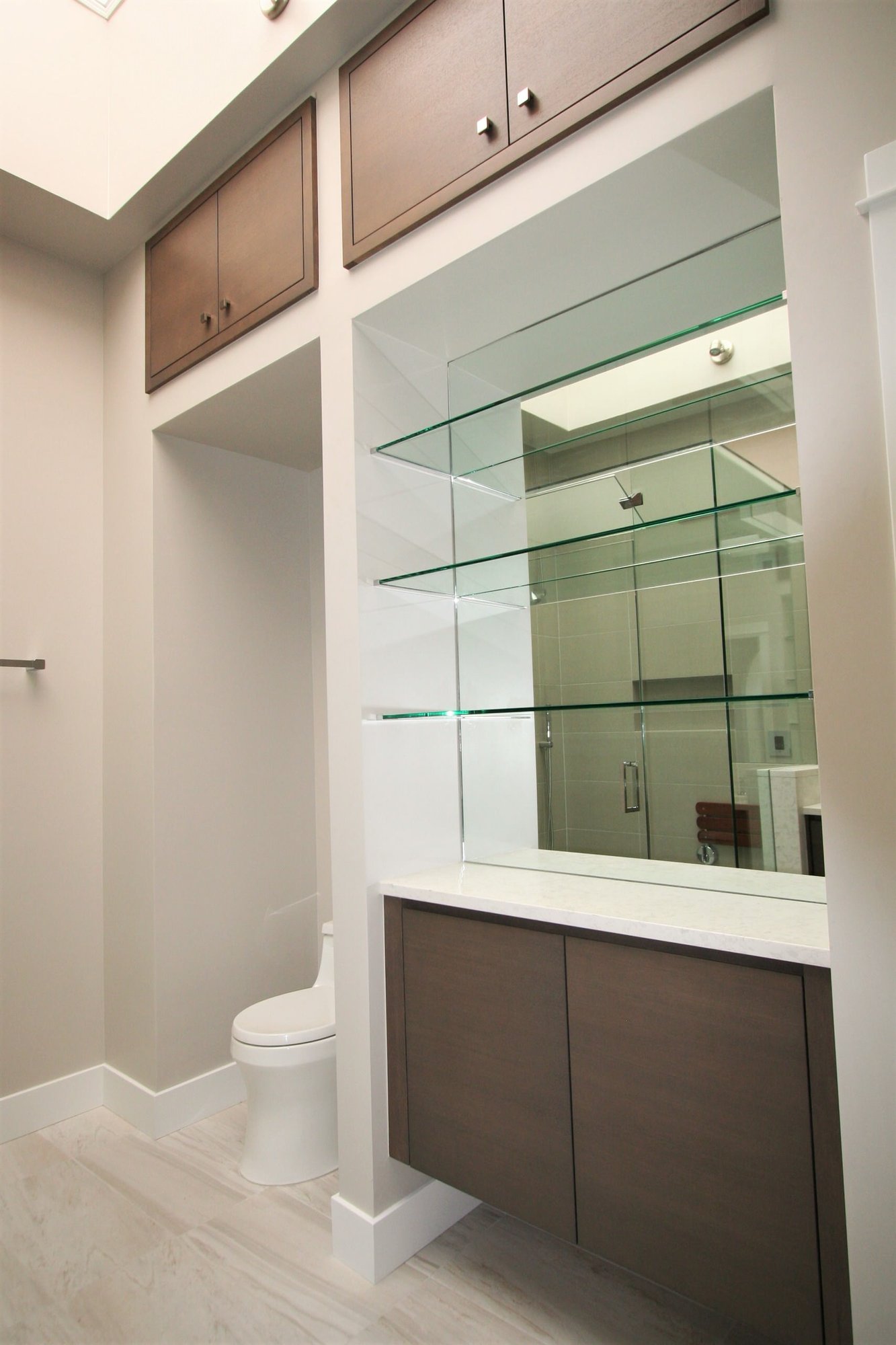 Mid-sized contemporary master corner shower with flat-panel cabinets, medium tone wood cabinets, a one-piece toilet, an undermount sink, marble countertops and a hinged shower door, by Jensen Design in Telluride, CO