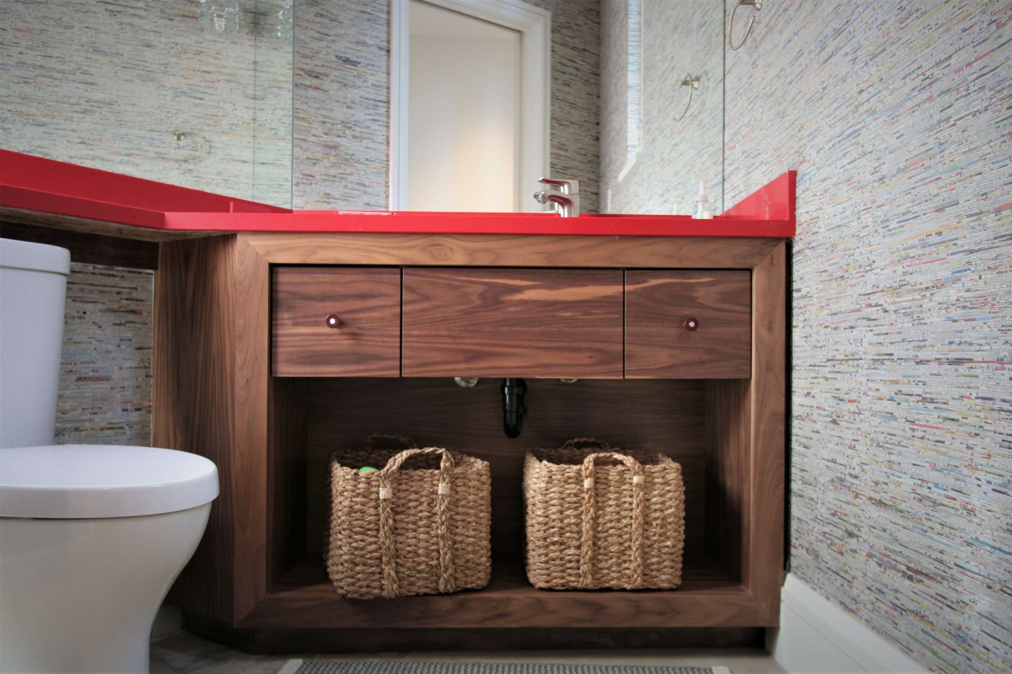 Small trendy powder room with open cabinets, medium tone wood cabinets, a one-piece toilet, an undermount sink, solid surface countertops and gray walls, by Jensen Design in Mountain Village, CO