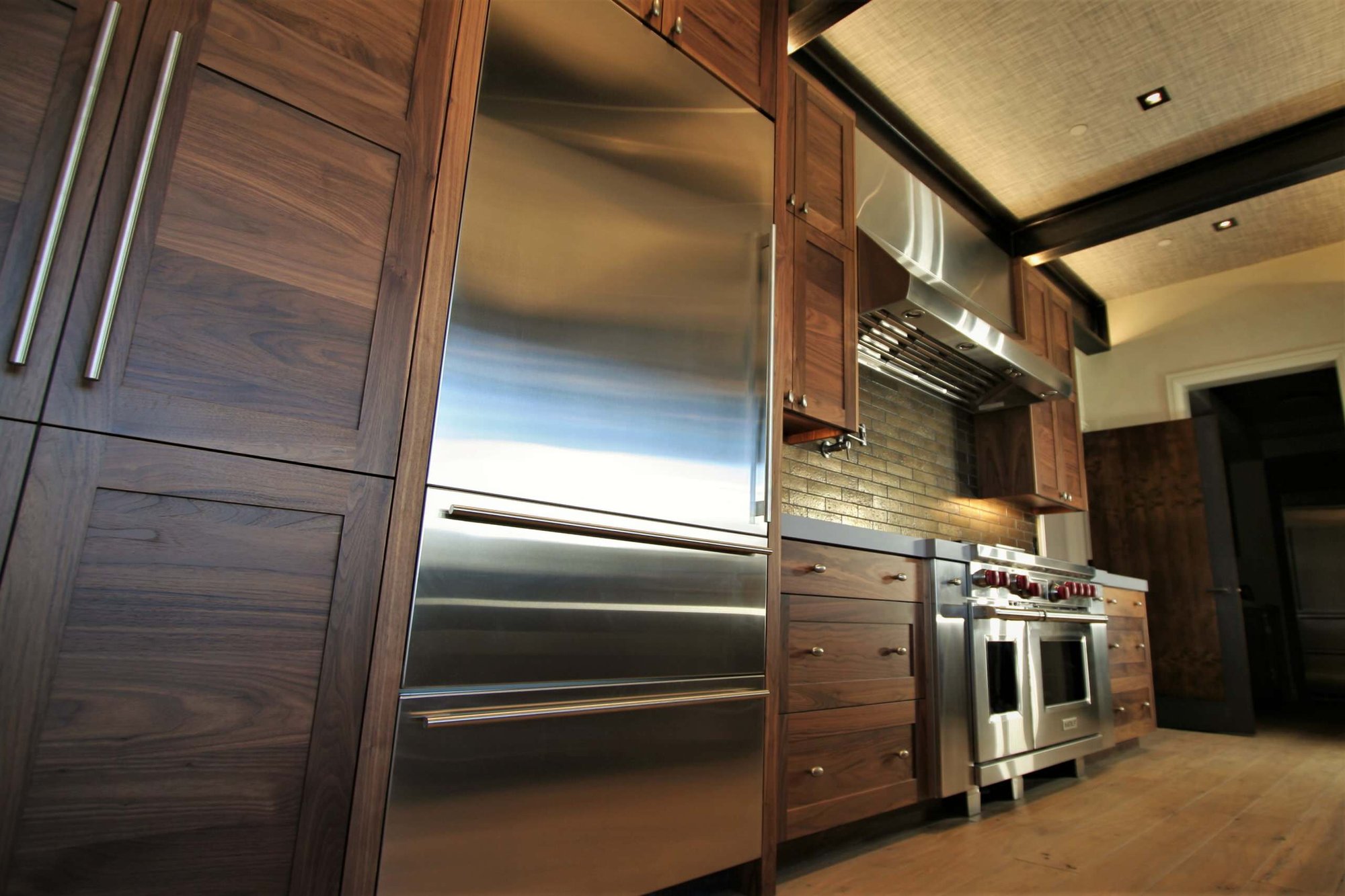 Mid-sized trendy galley light wood floor and brown floor open concept kitchen with a farmhouse sink, shaker cabinets, medium tone wood cabinets, concrete countertops, stainless steel appliances, an island, brown backsplash and stone tile backsplash, by Jensen Design in Mountain Village, CO