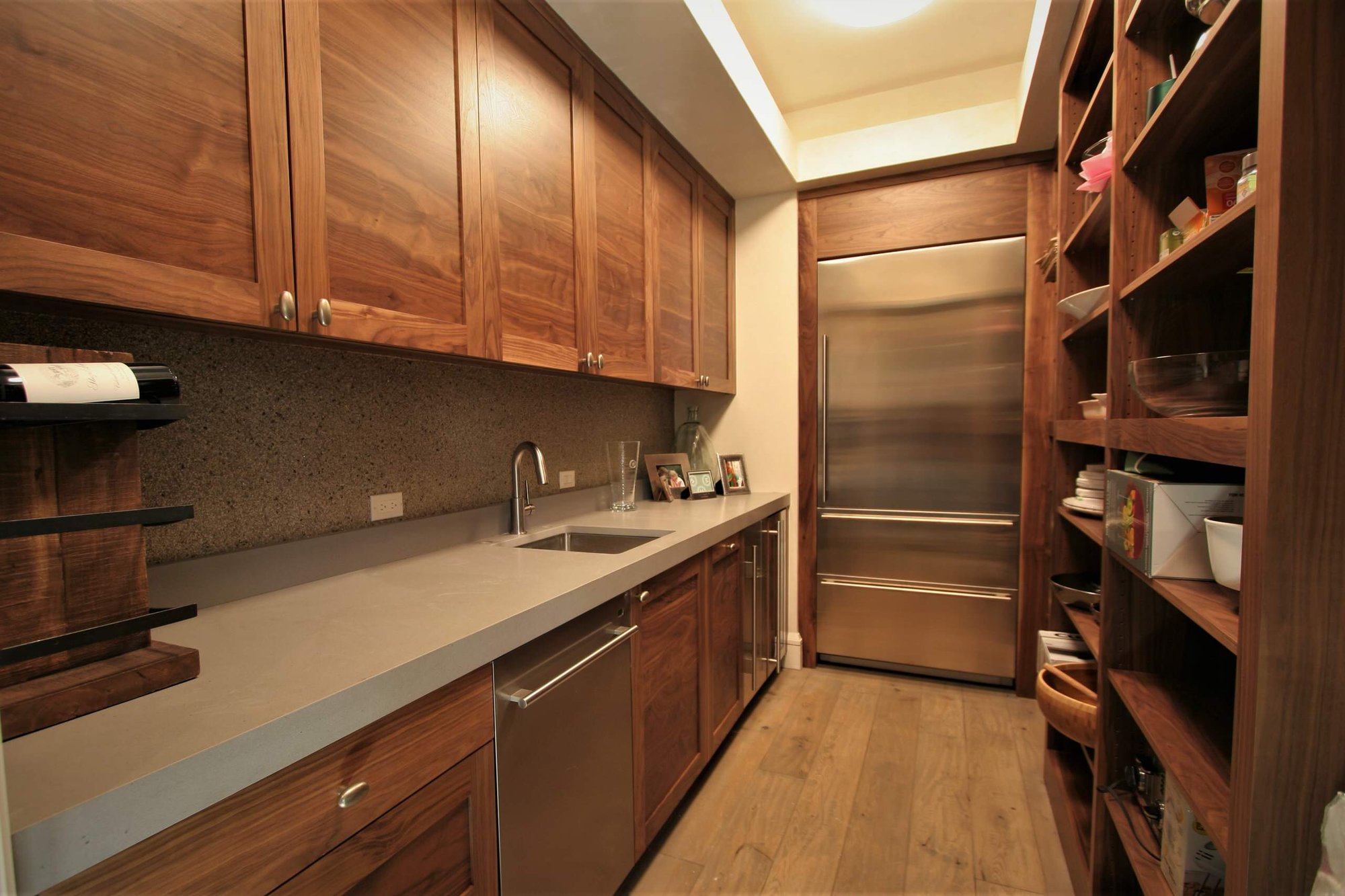 Mid-sized trendy galley light wood floor and brown floor open concept kitchen with shaker cabinets, medium tone wood cabinets, concrete countertops, stainless steel appliances, brown backsplash, an island and an undermount sink, by Jensen Design in Mountain Village, CO