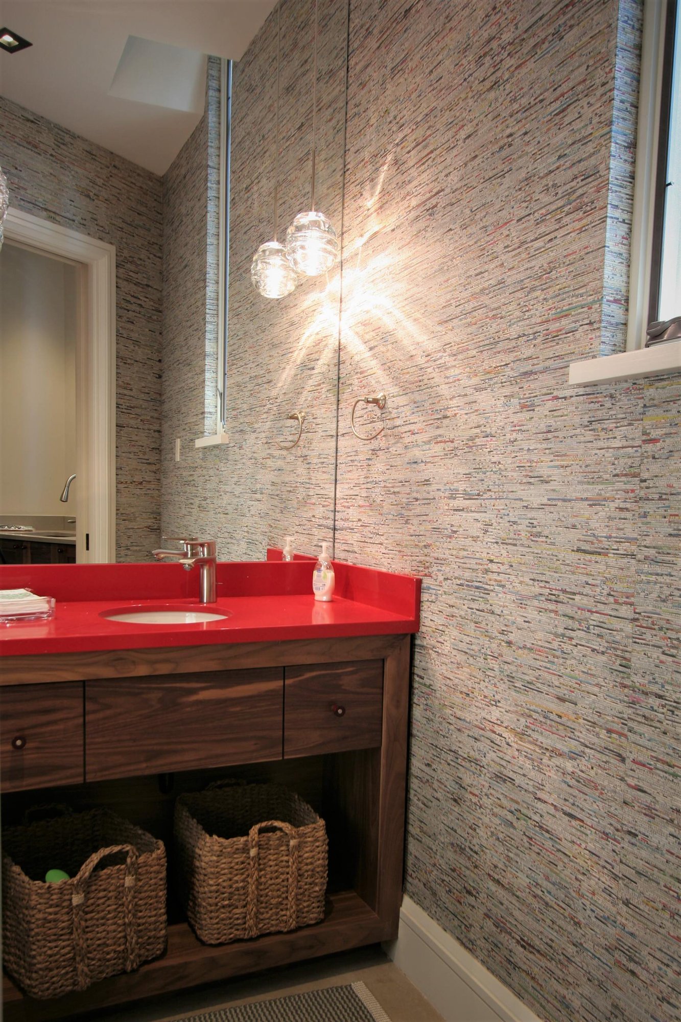 Small trendy powder room with open cabinets, medium tone wood cabinets, a one-piece toilet, an undermount sink, solid surface countertops and gray walls, by Jensen Design in Mountain Village, CO