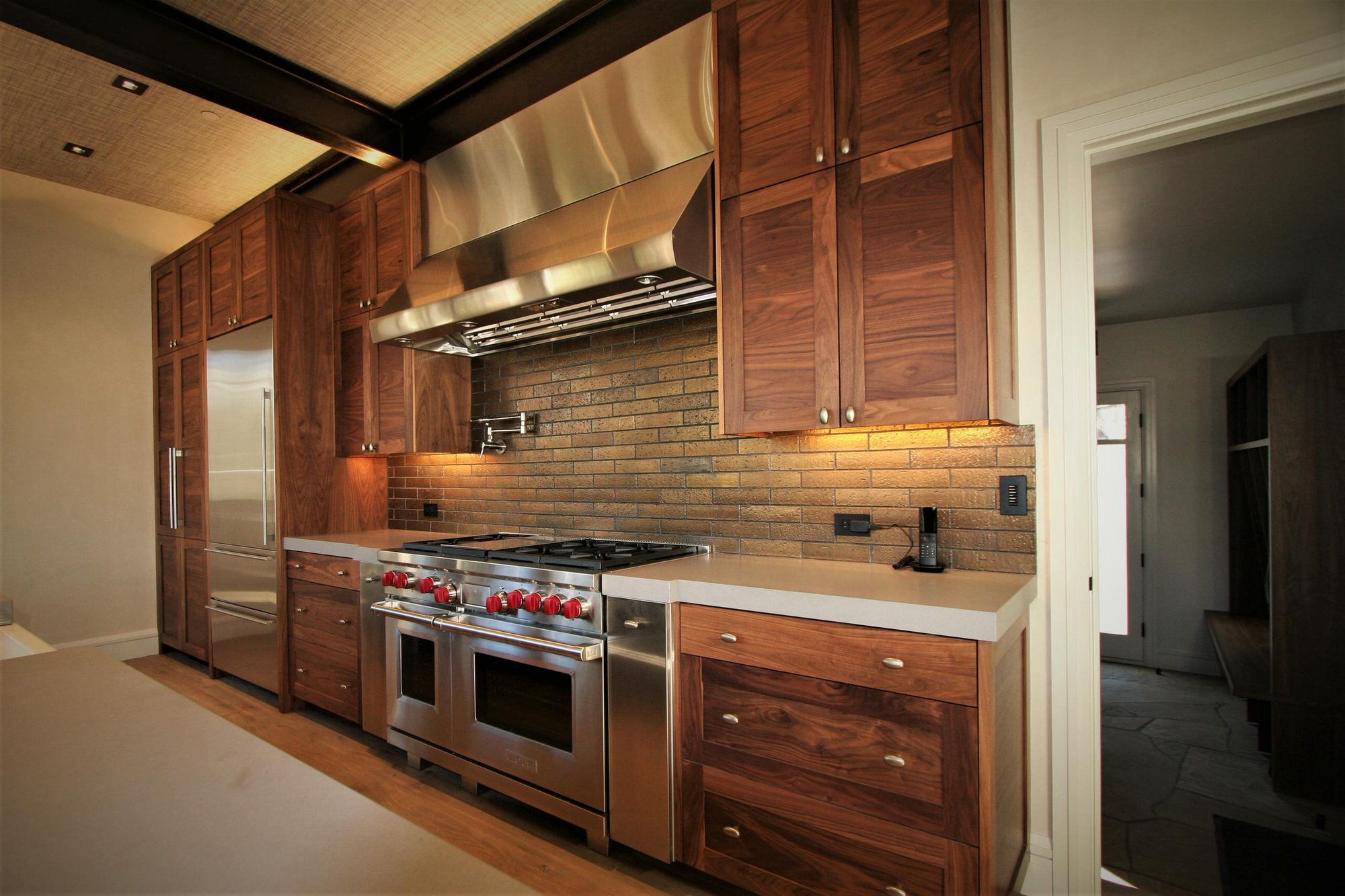 Mid-sized contemporary galley light wood floor and brown floor open concept kitchen with a farmhouse sink, shaker cabinets, medium tone wood cabinets, concrete countertops, stainless steel appliances, an island, brown backsplash and stone tile backsplash, by Jensen Design in Mountain Village, CO
