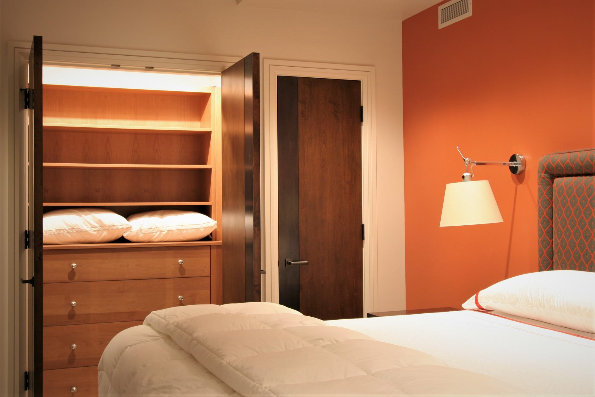 Small trendy gender-neutral reach-in closet with flat-panel cabinets and medium tone wood cabinets, by Jensen Design in Mountain Village, CO