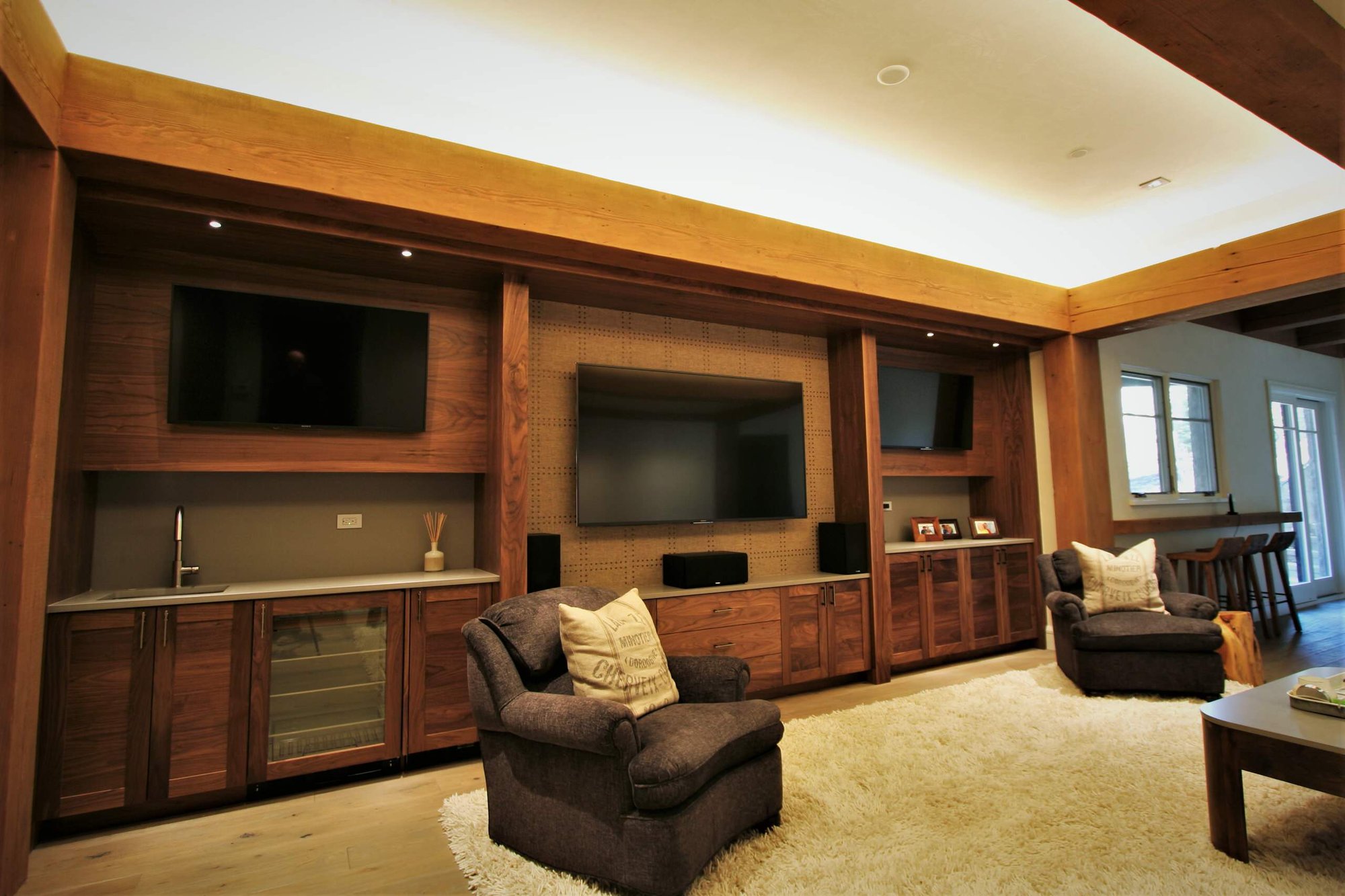 Large trendy open concept light wood floor and brown floor home theater with a wall-mounted tv and blue walls, by Jensen Design in Mountain Village, CO