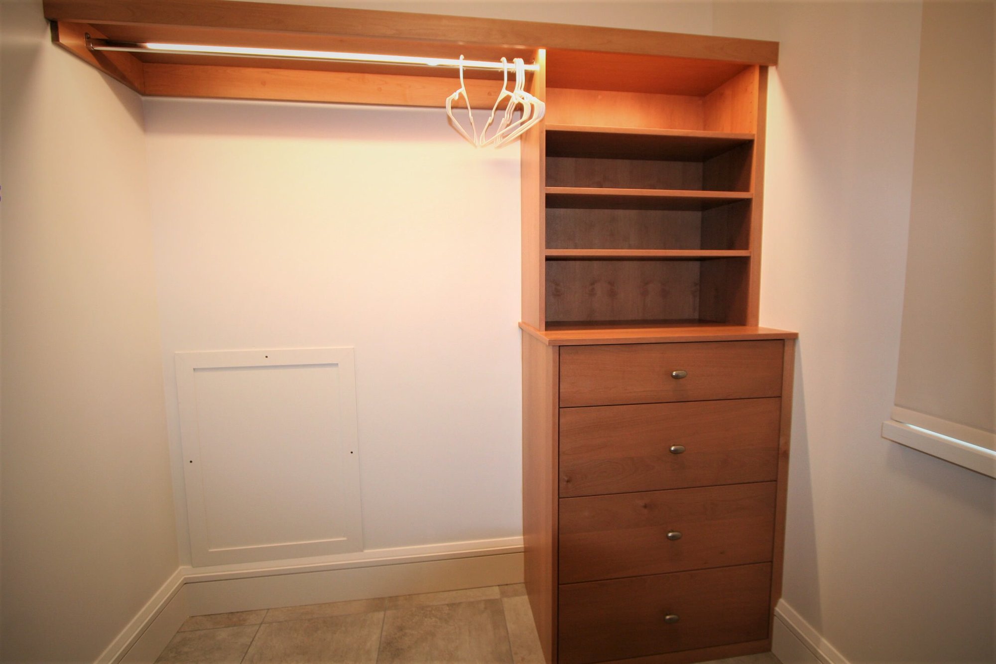 Small classic gender-neutral ceramic tile and beige floor walk-in closet with flat-panel cabinets and medium tone wood cabinets, by Jensen Design in Mountain Village, CO