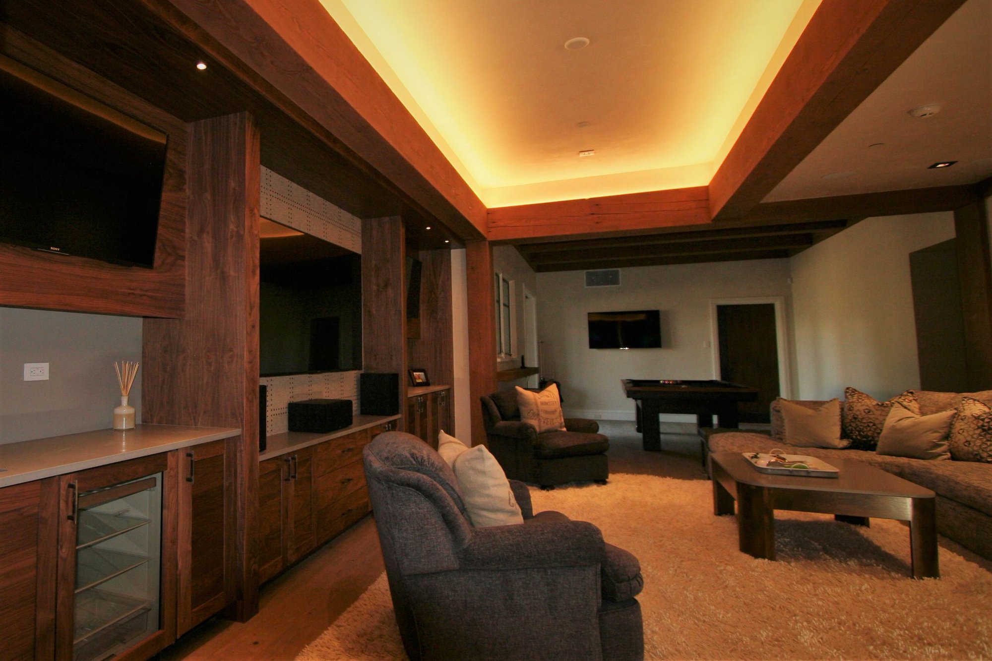 Large contemporary open concept light wood floor and brown floor home theater with a wall-mounted tv and blue walls, by Jensen Design in Mountain Village, CO