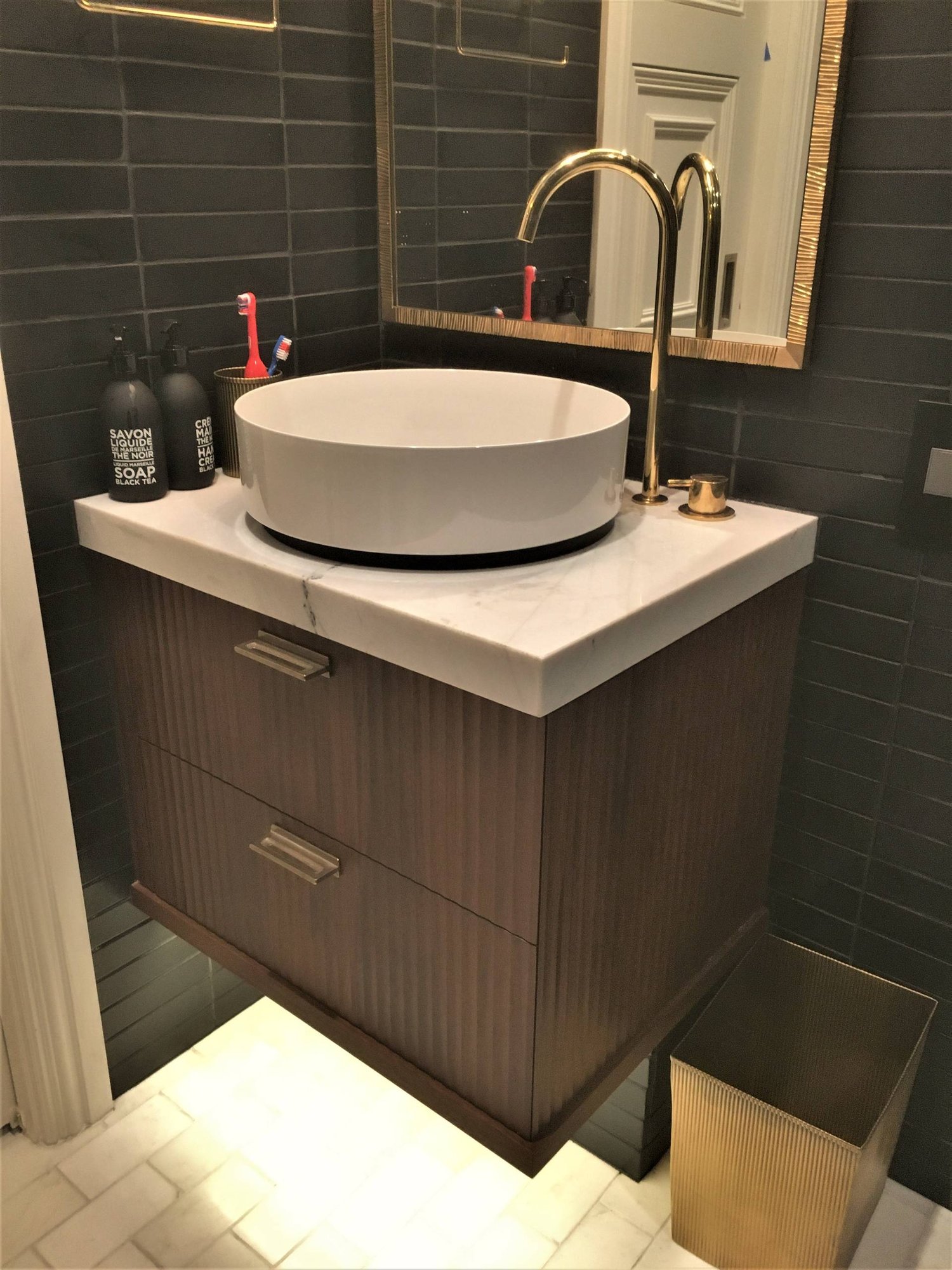 Small minimalist 3/4 black tile marble floor and white floor walk-in shower with flat-panel cabinets, dark wood cabinets, black walls, a vessel sink, marble countertops and a hinged shower door, by Jensen Design in Telluride, CO