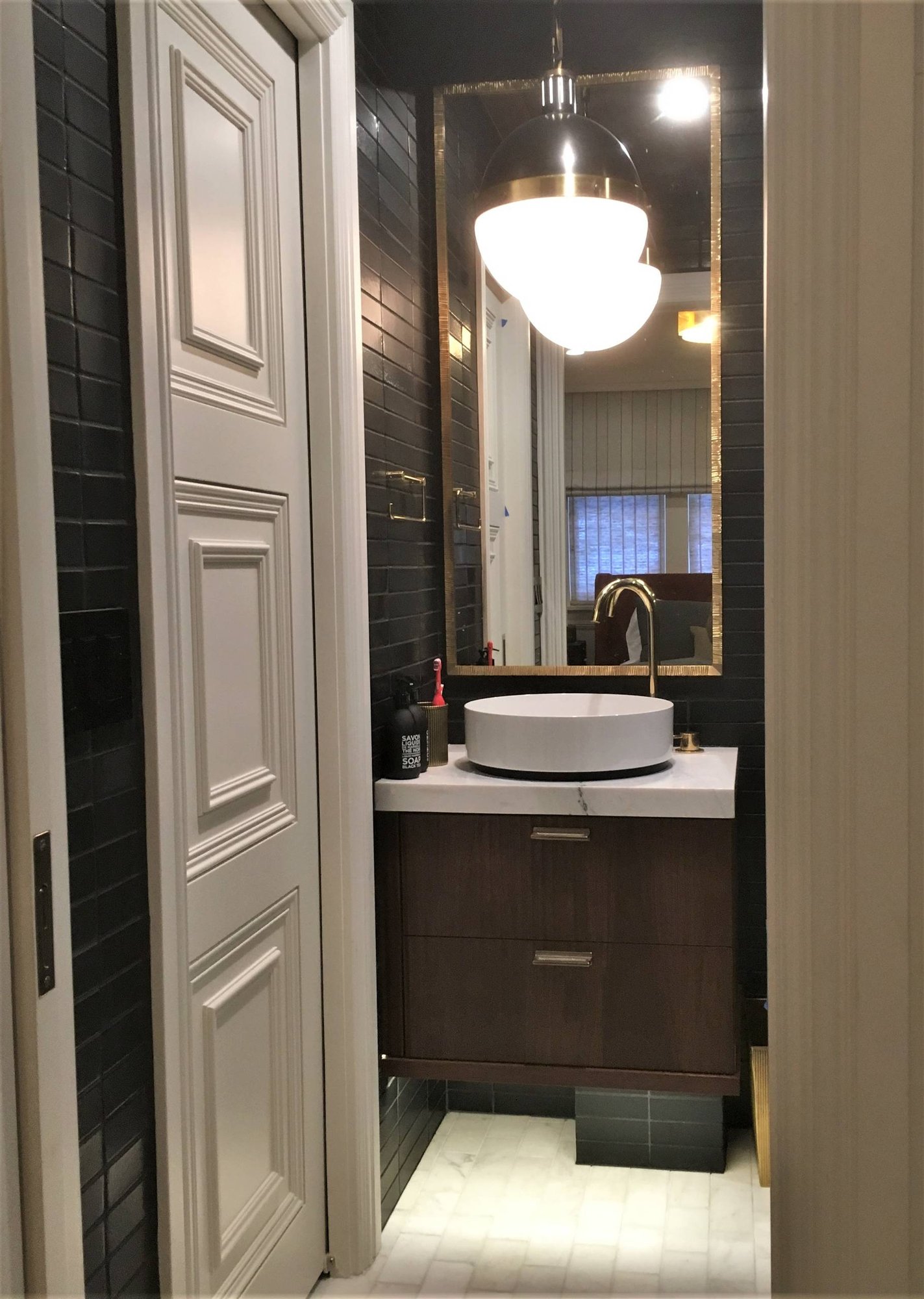 Small minimalist 3/4 black tile marble floor and white floor walk-in shower with flat-panel cabinets, dark wood cabinets, black walls, a vessel sink, marble countertops and a hinged shower door, by Jensen Design in Telluride, CO