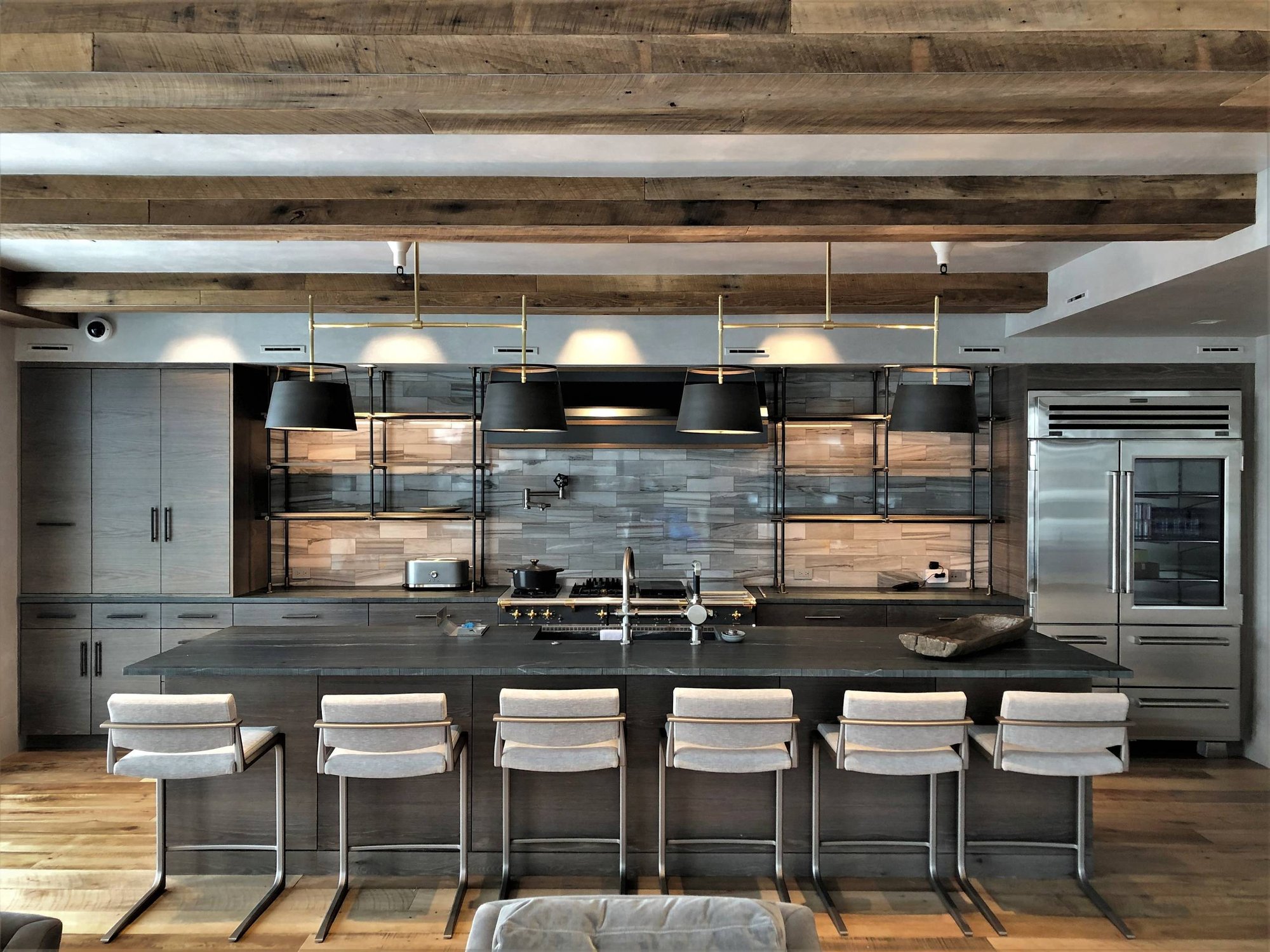 Large contemporary u-shaped medium tone wood floor and brown floor eat-in kitchen with a farmhouse sink, flat-panel cabinets, light wood cabinets, stainless steel appliances, an island, black countertops, soapstone countertops, gray backsplash and marble backsplash, by Jensen Design in Mountain Vill