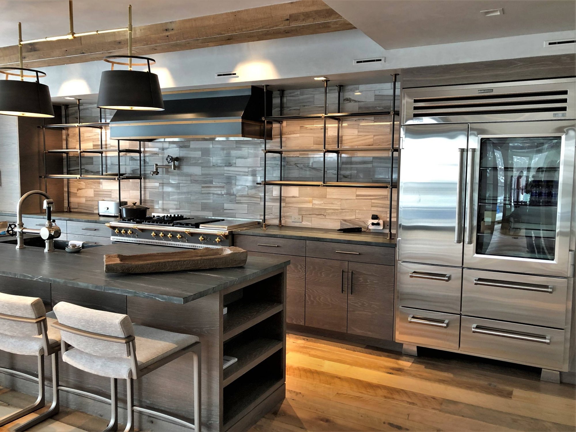Large contemporary u-shaped medium tone wood floor and brown floor eat-in kitchen with a farmhouse sink, flat-panel cabinets, light wood cabinets, quartzite countertops, beige backsplash, porcelain backsplash, stainless steel appliances, an island and black countertops, by Jensen Design in Mountain 