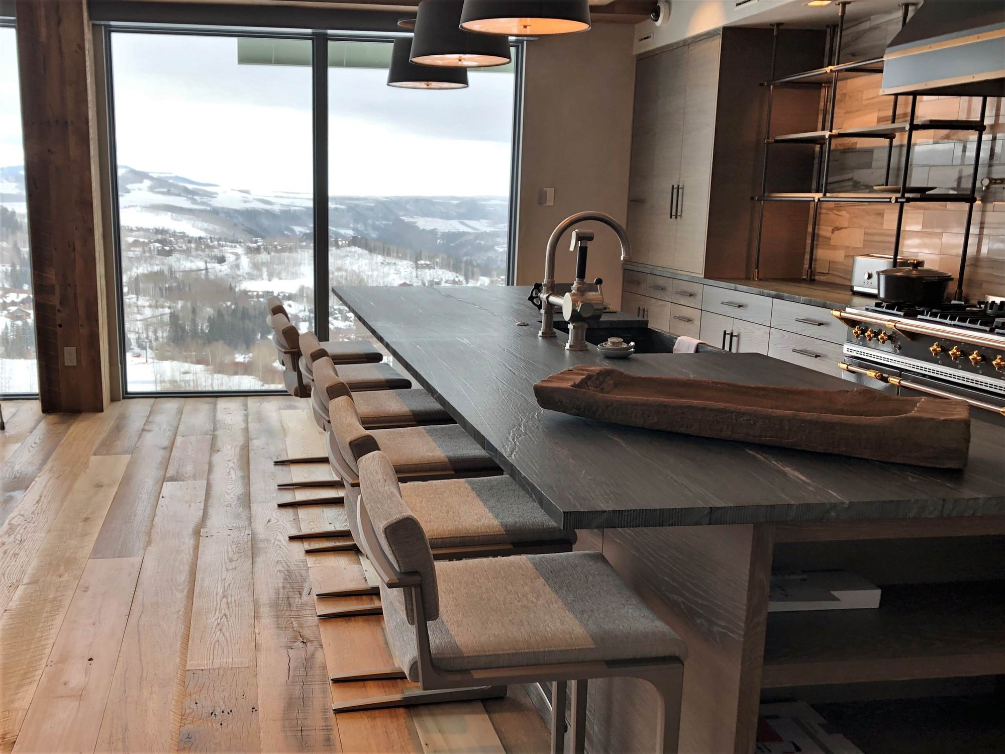 Large contemporary u-shaped medium tone wood floor and brown floor eat-in kitchen with a farmhouse sink, flat-panel cabinets, light wood cabinets, quartzite countertops, beige backsplash, porcelain backsplash, stainless steel appliances, an island and black countertops, by Jensen Design in Mountain 