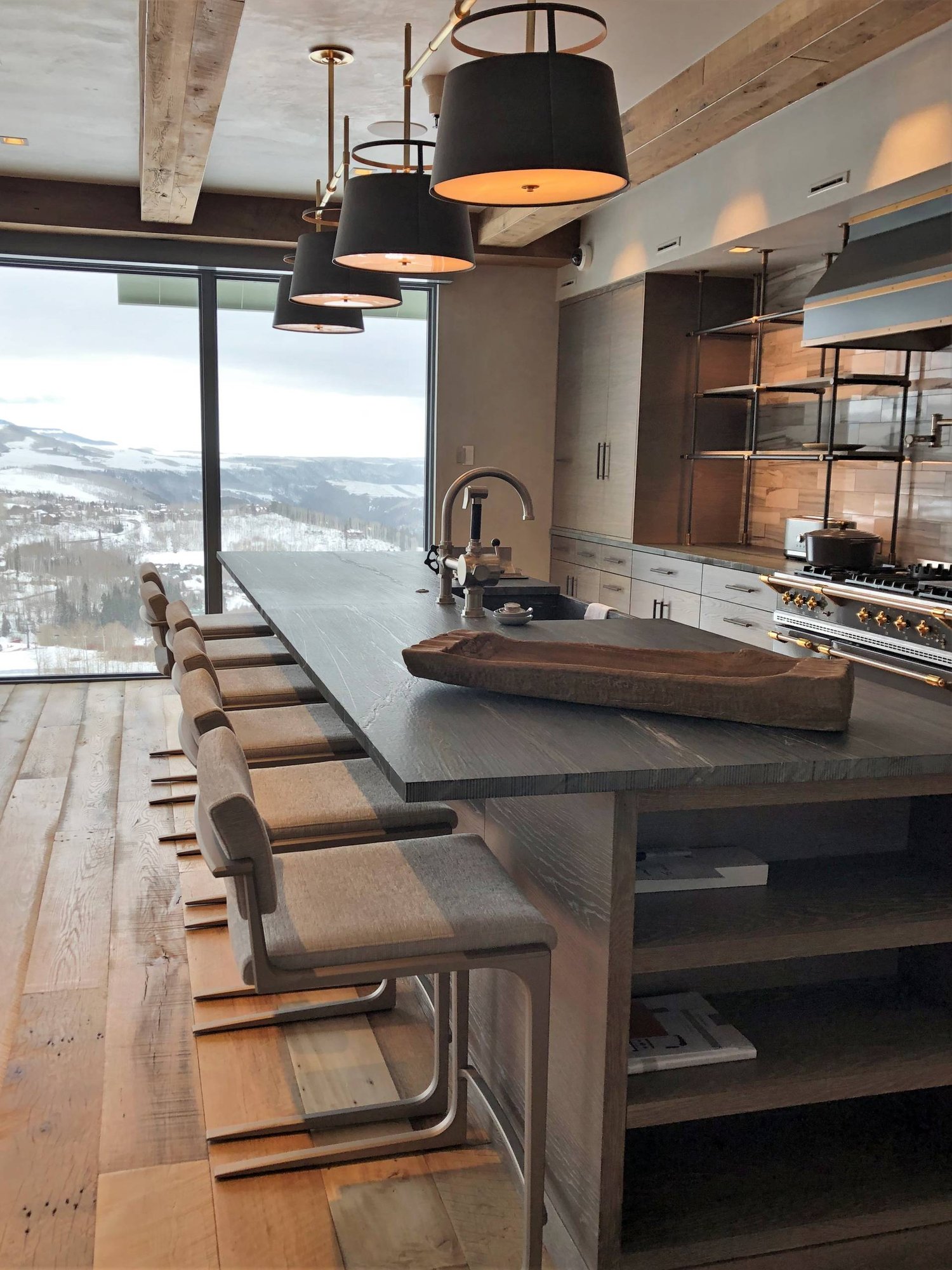 Large contemporary u-shaped medium tone wood floor and brown floor eat-in kitchen with a farmhouse sink, flat-panel cabinets, light wood cabinets, quartzite countertops, beige backsplash, porcelain backsplash, stainless steel appliances, an island and black countertops, by Jensen Design in Mountain 
