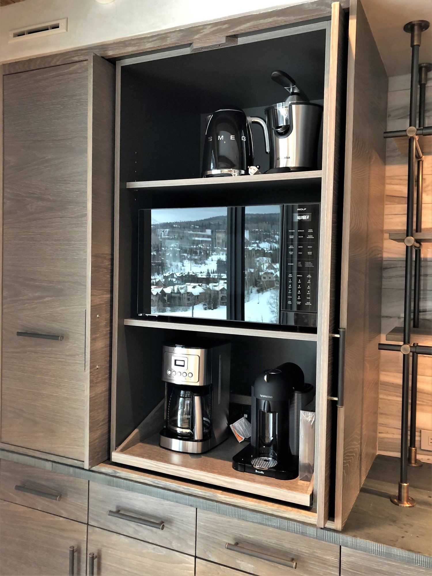 Large trendy u-shaped medium tone wood floor and brown floor eat-in kitchen with a farmhouse sink, flat-panel cabinets, light wood cabinets, stainless steel appliances, an island, concrete countertops, gray backsplash, marble backsplash and gray countertops, by Jensen Design in Mountain Village, CO