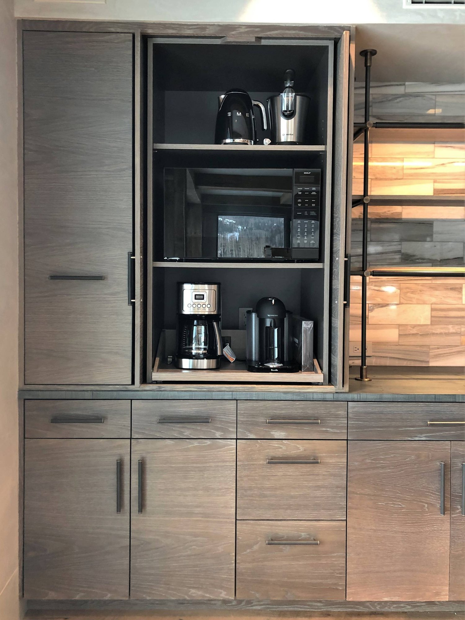 Large trendy u-shaped medium tone wood floor and brown floor eat-in kitchen with a farmhouse sink, flat-panel cabinets, light wood cabinets, stainless steel appliances, an island, concrete countertops, gray backsplash, marble backsplash and gray countertops, by Jensen Design in Mountain Village, CO