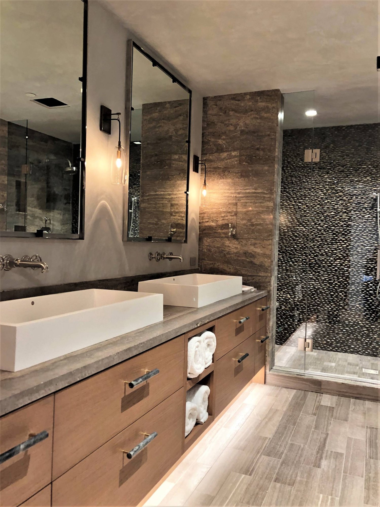 Large trendy master stone tile porcelain tile and gray floor alcove shower with flat-panel cabinets, medium tone wood cabinets, a two-piece toilet, multicolored walls, a vessel sink, concrete countertops, a hinged shower door and gray countertops, by Jensen Design in Mountain Village, CO