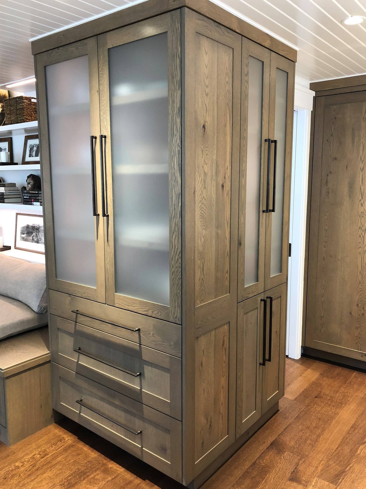 Small trendy gender-neutral medium tone wood floor and brown floor reach-in closet with glass-front cabinets and light wood cabinets, by Jensen Design in Telluride, CO