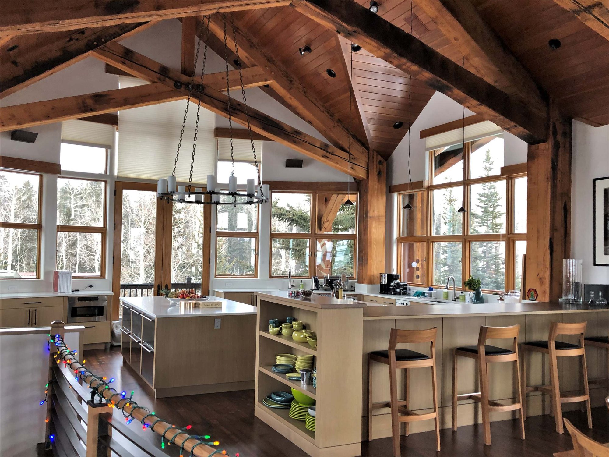 Huge mountain style u-shaped dark wood floor and brown floor eat-in kitchen with an undermount sink, flat-panel cabinets, light wood cabinets, stainless steel appliances, two islands and white countertops, by Jensen Design in Telluride, CO