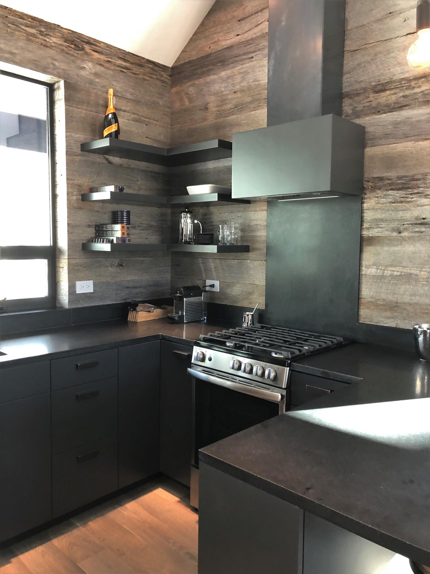 Mid-sized trendy u-shaped light wood floor, orange floor and vaulted ceiling open concept kitchen with an undermount sink, flat-panel cabinets, black cabinets, brown backsplash, stainless steel appliances, a peninsula and brown countertops, by Jensen Design in Telluride, CO
