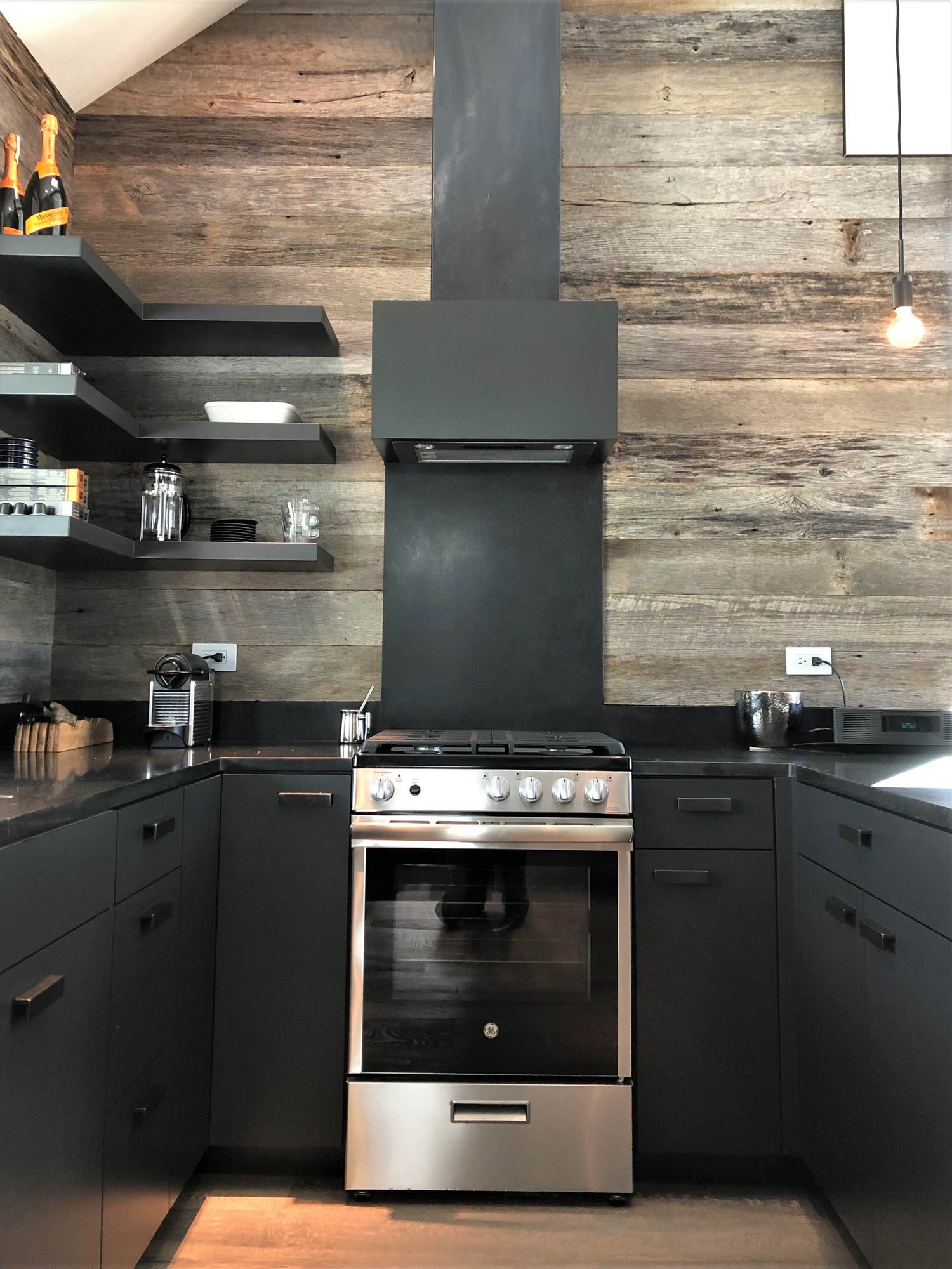 Mid-sized contemporary u-shaped light wood floor, orange floor and vaulted ceiling open concept kitchen with an undermount sink, flat-panel cabinets, black cabinets, brown backsplash, stainless steel appliances, a peninsula and brown countertops, by Jensen Design in Telluride, CO