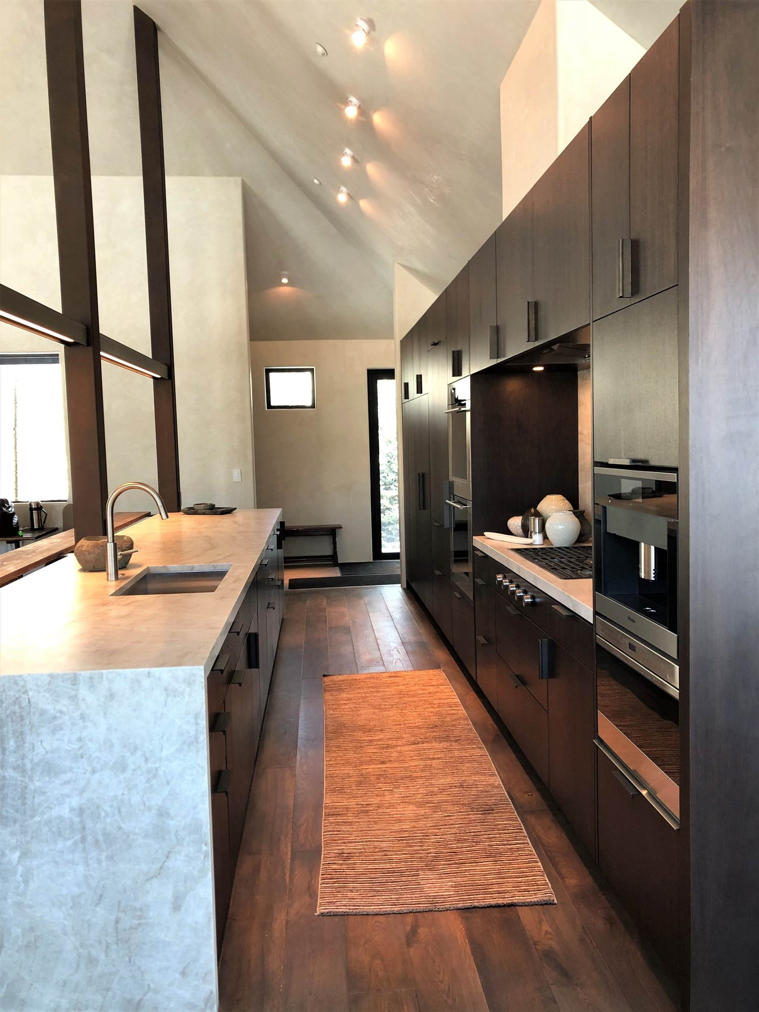 Large contemporary galley medium tone wood floor, brown floor and vaulted ceiling open concept kitchen with an undermount sink, flat-panel cabinets, dark wood cabinets, colored appliances, an island and multicolored countertops, by Jensen Design in Telluride, CO