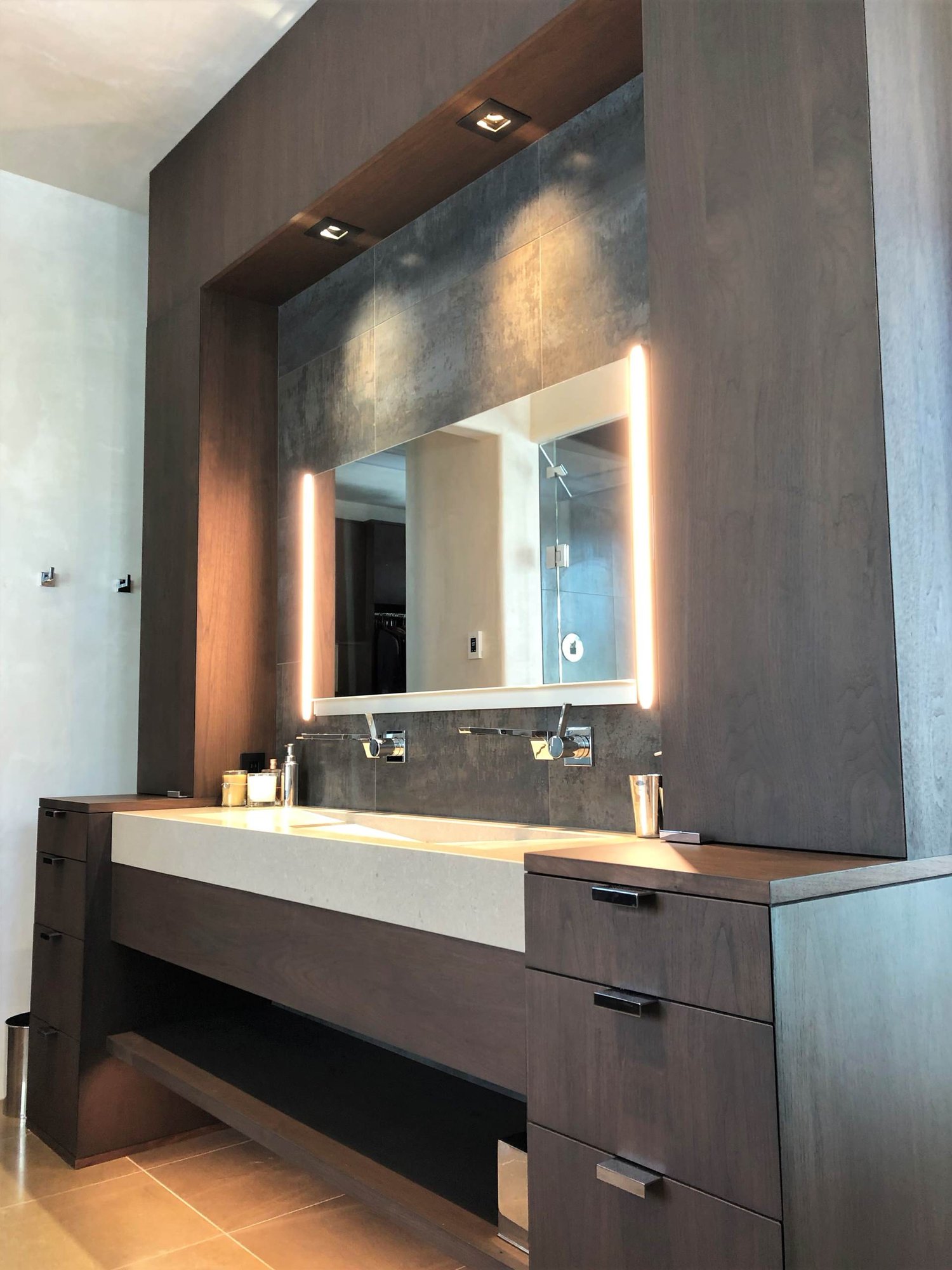 Mid-sized trendy master gray tile brown floor and double-sink bathroom with flat-panel cabinets, dark wood cabinets, beige walls, a trough sink, a hinged shower door, beige countertops and a built-in vanity, by Jensen Design in Telluride, CO