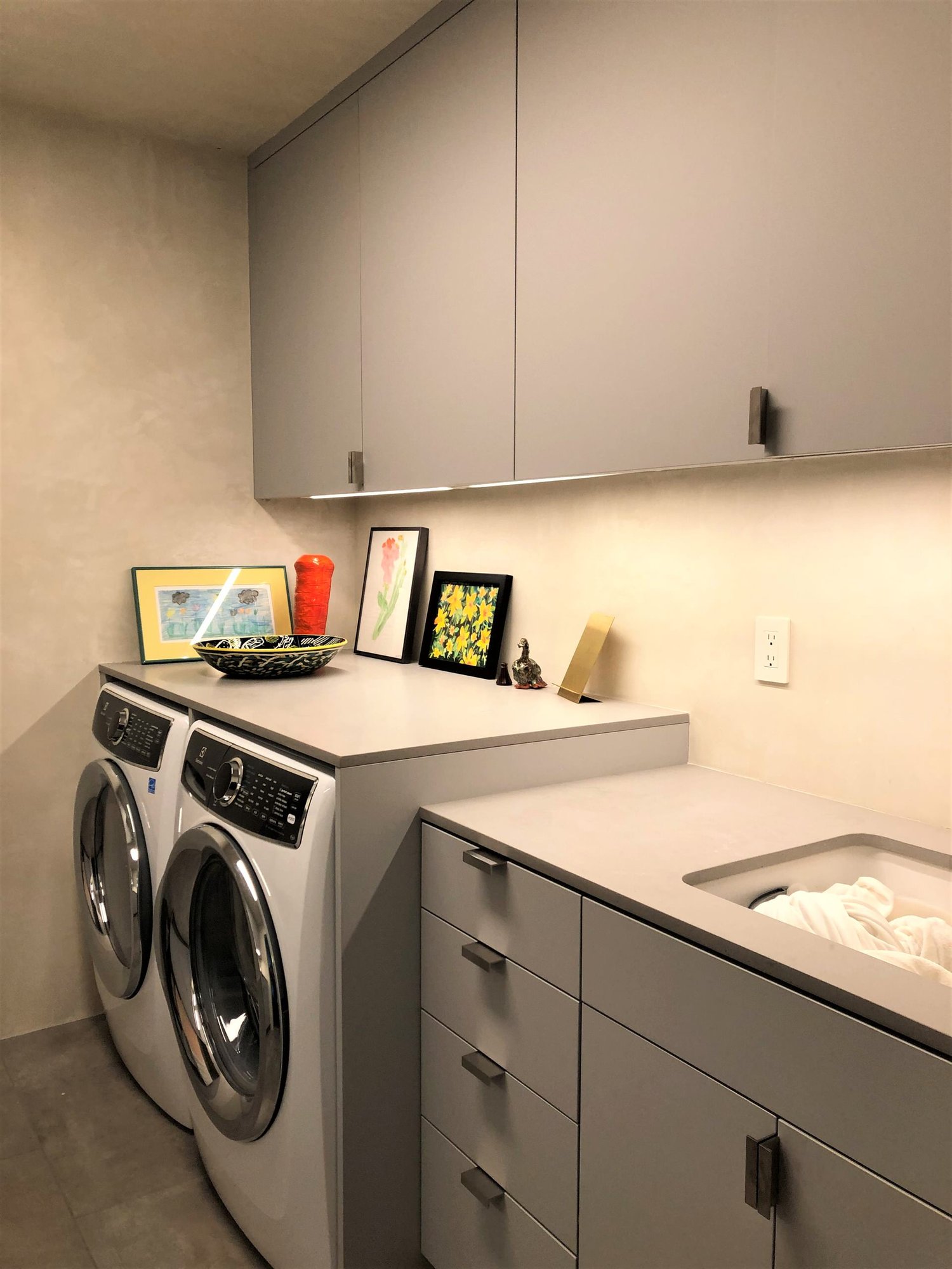 Mid-sized contemporary galley gray floor dedicated laundry room with an undermount sink, flat-panel cabinets, gray cabinets, beige walls, a side-by-side washer/dryer and gray countertops, by Jensen Design in Telluride, CO