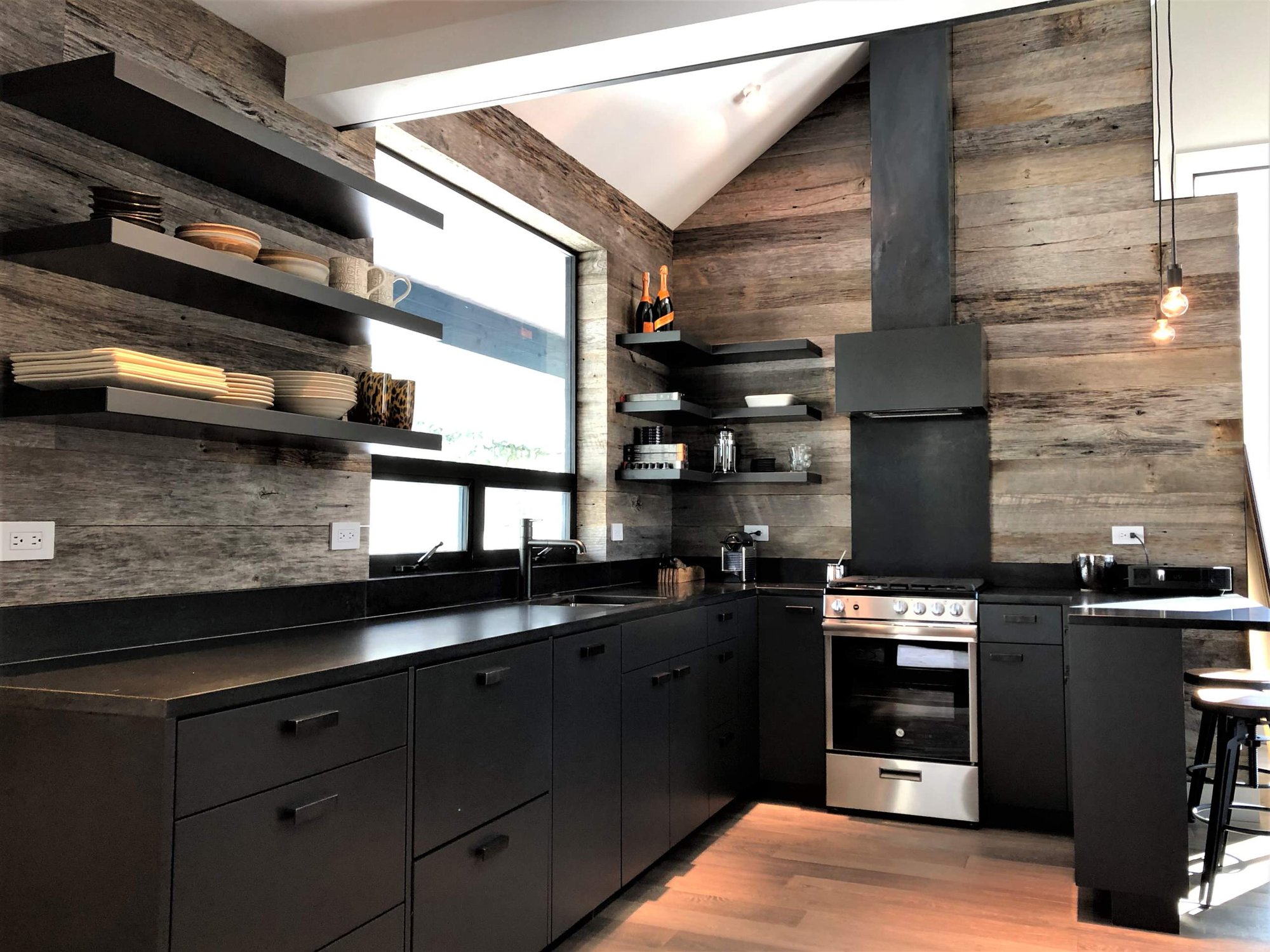 Mid-sized contemporary u-shaped light wood floor, orange floor and vaulted ceiling open concept kitchen with an undermount sink, flat-panel cabinets, black cabinets, brown backsplash, stainless steel appliances, a peninsula and brown countertops, by Jensen Design in Telluride, CO