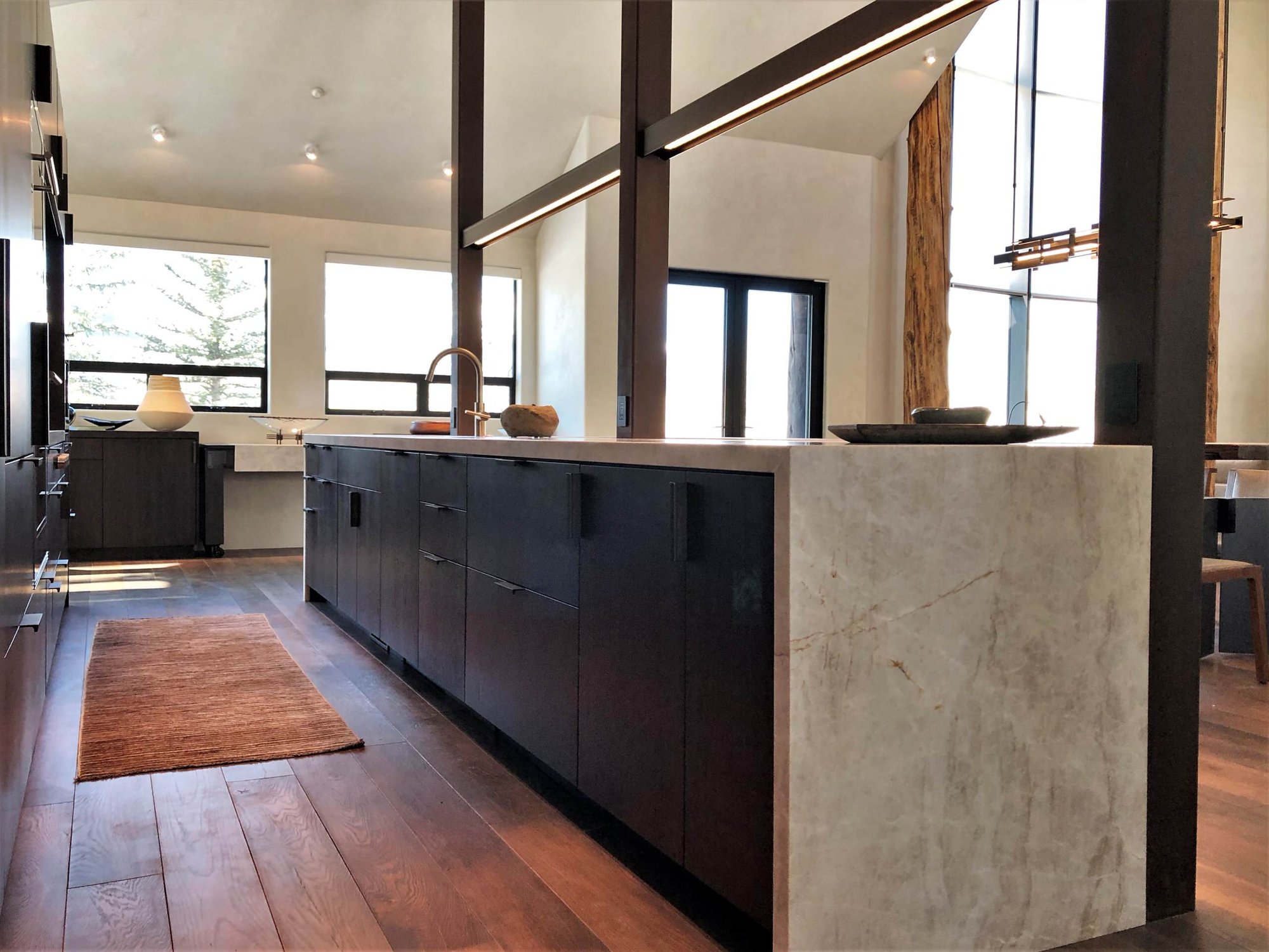 Large trendy galley medium tone wood floor, brown floor and vaulted ceiling open concept kitchen with an undermount sink, flat-panel cabinets, dark wood cabinets, colored appliances, an island and multicolored countertops, by Jensen Design in Telluride, CO
